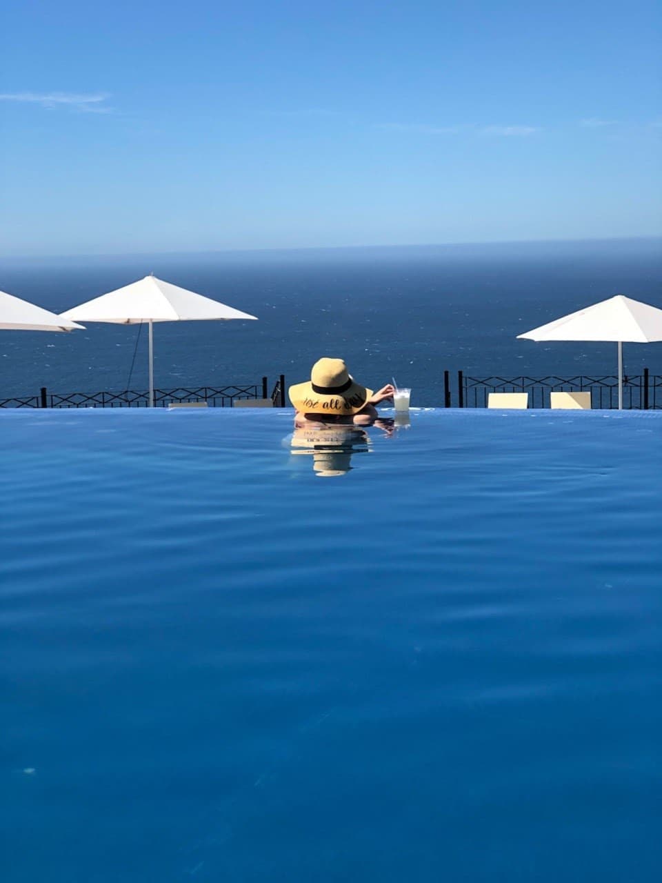 Picture of Nicole in an infinity pool in a sun hat looking over the ocean.