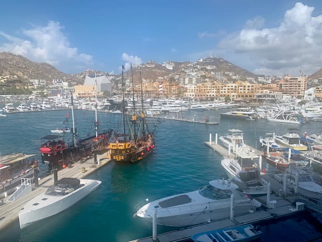 A beautiful view of a large boat dock with mountains and a town in the distance.