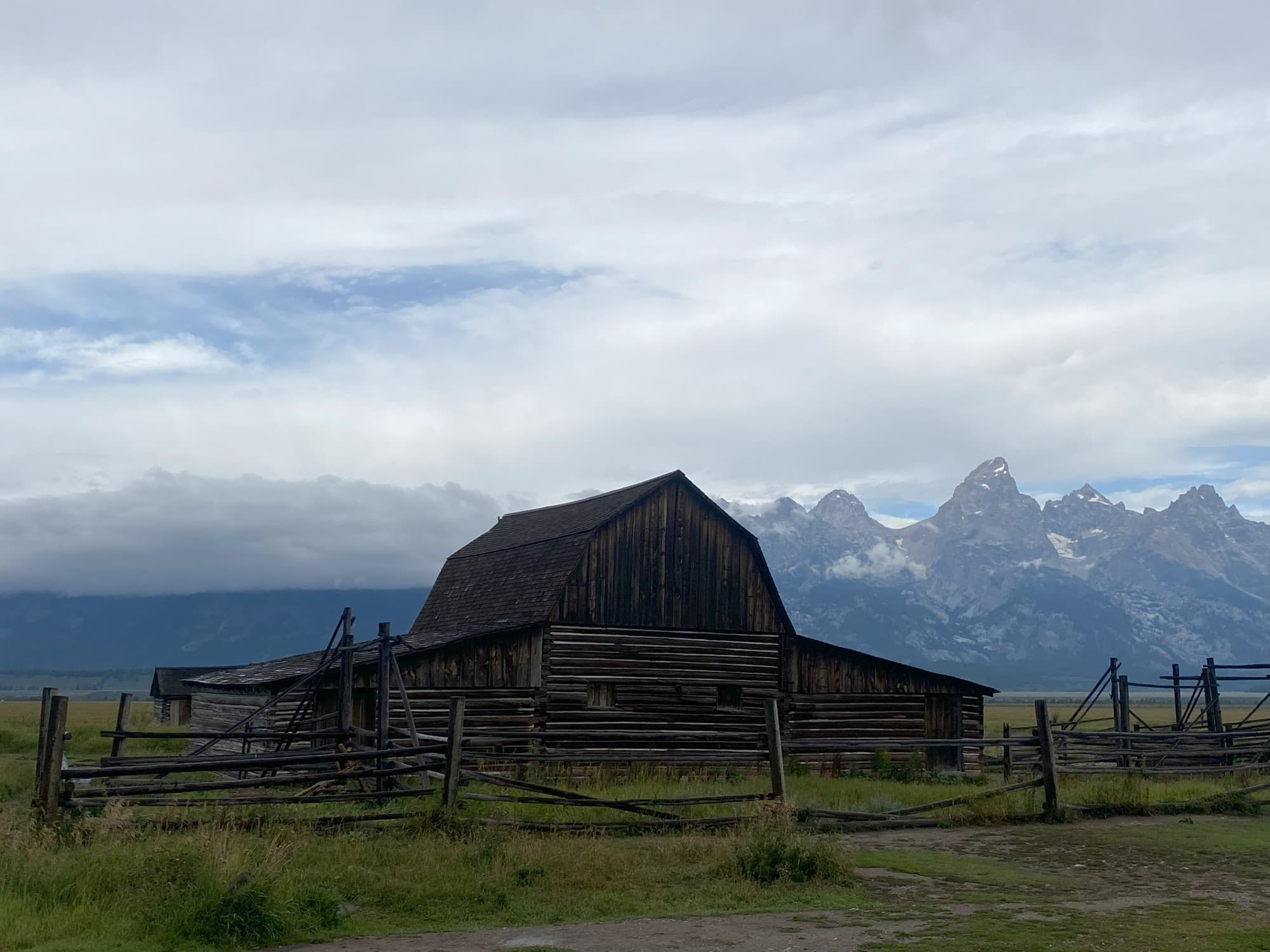 A log cabin with mountains at the back.