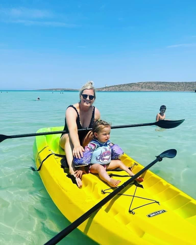Picture of Nicole with a child on a yellow kayak in the ocean.