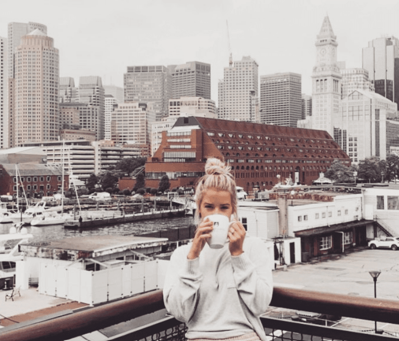 Picture of Sara wearing white shirt and drinking coffee