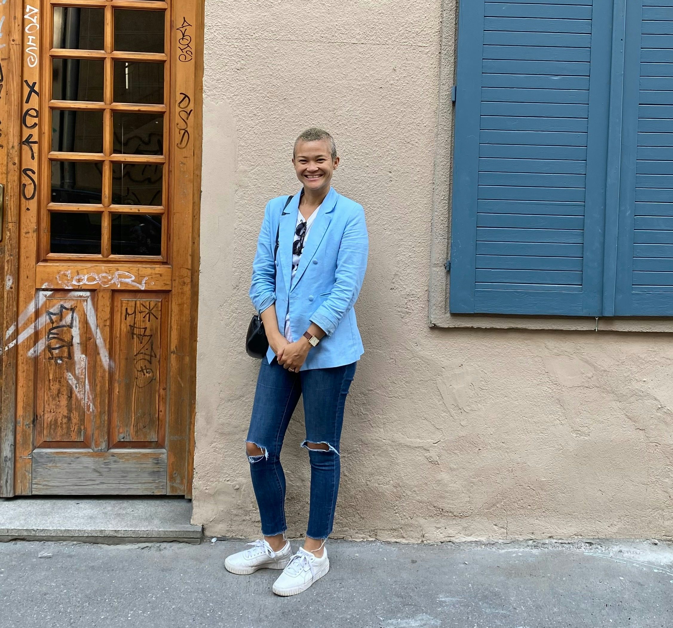 Travel advisor Sequoia Armstrong posing in front of a stone wall and wooden door, while wearing a light blue top.