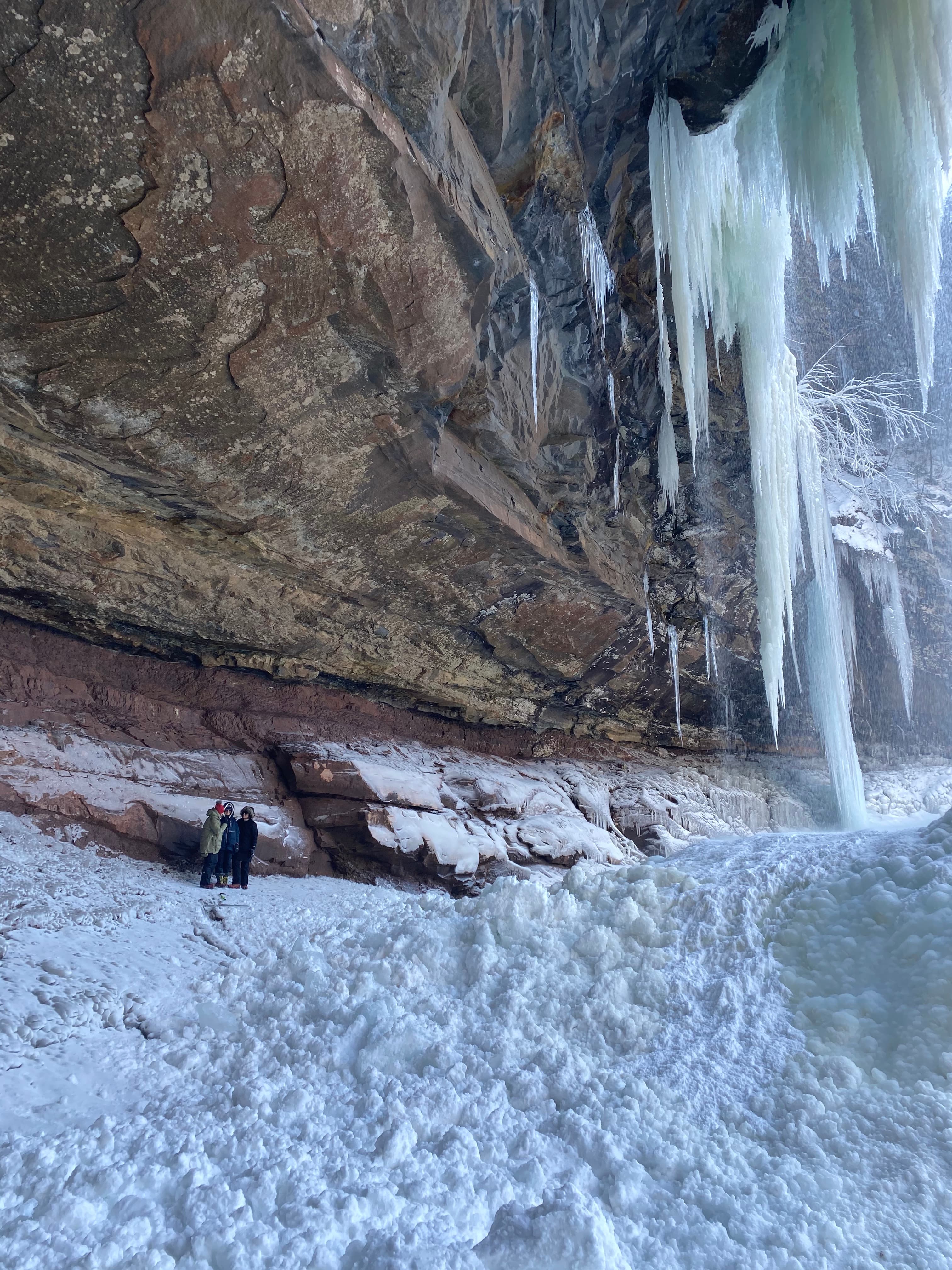 two people standing beneath a frozen waterfall