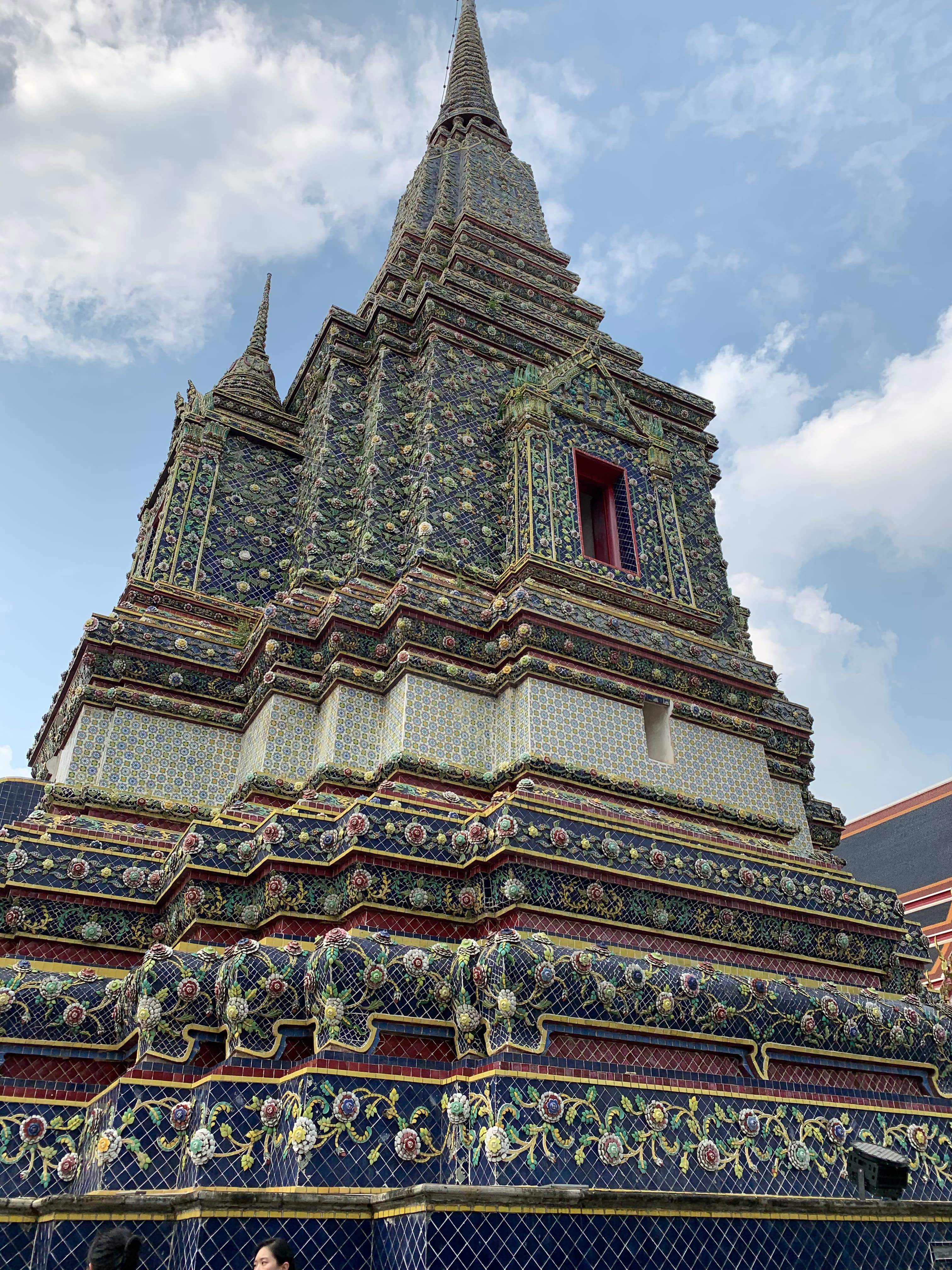 An RV parked beneath a rocky mountain scattered with green trees