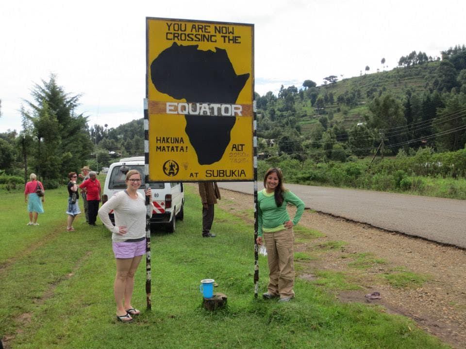 Travel advisor and her friend posing with a yellow board saying "You are crossing the equator"