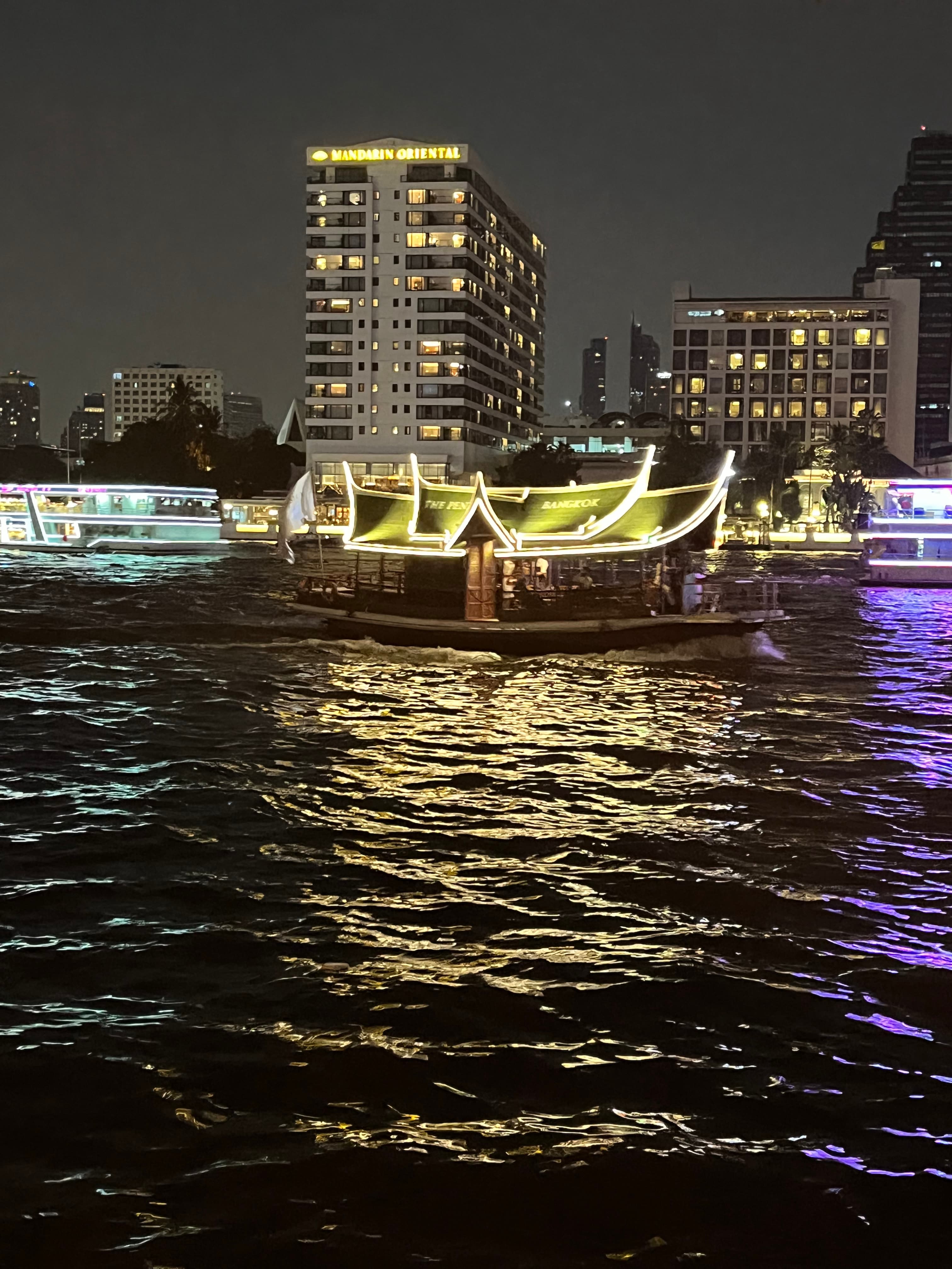 A picture of the Mandarin Hotel lit up at night over the water.