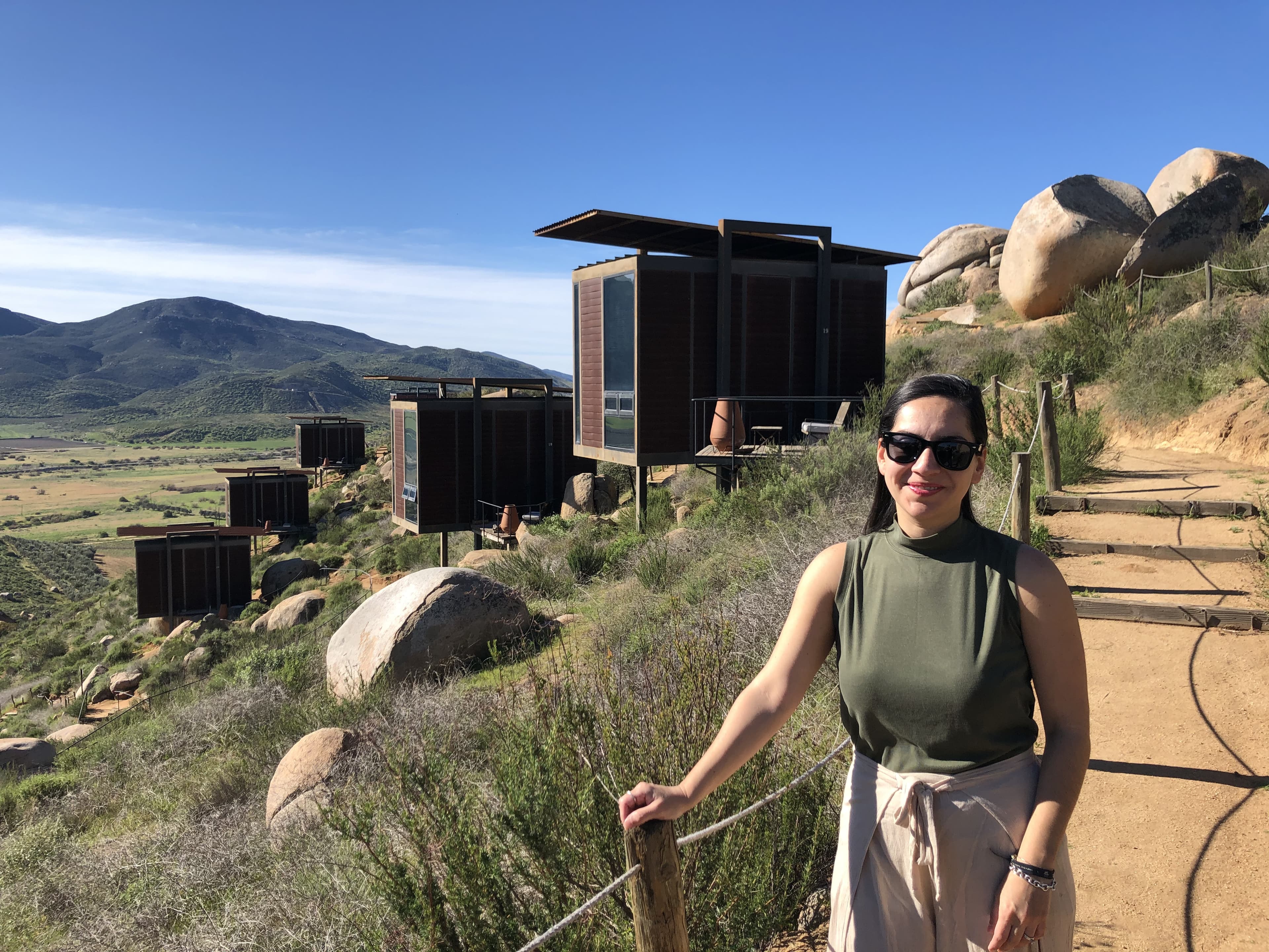 Advisor posing in front of a group of huts on the side of a hill