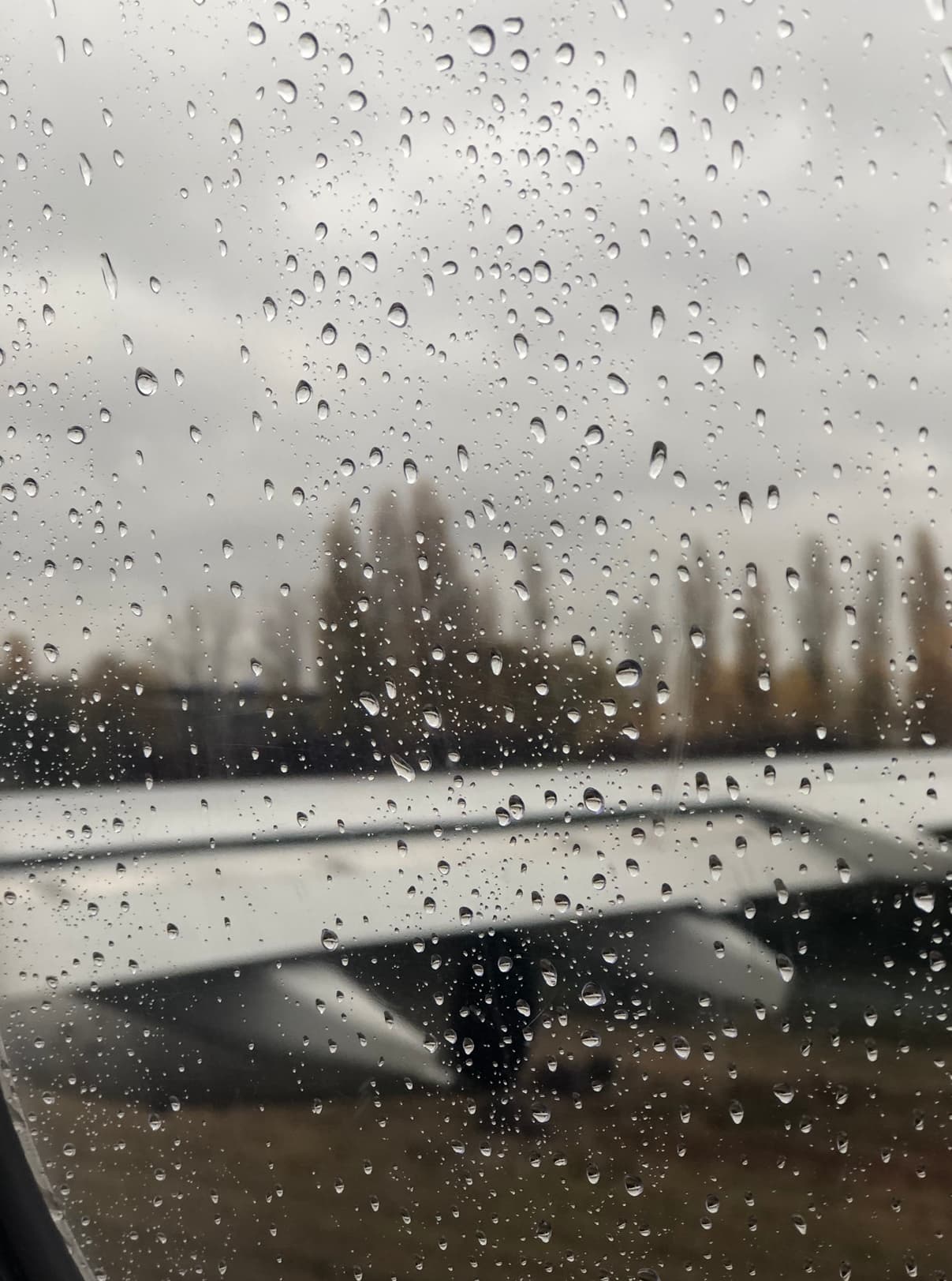 rain droplets on a plane window with a blurry city skyline in the background