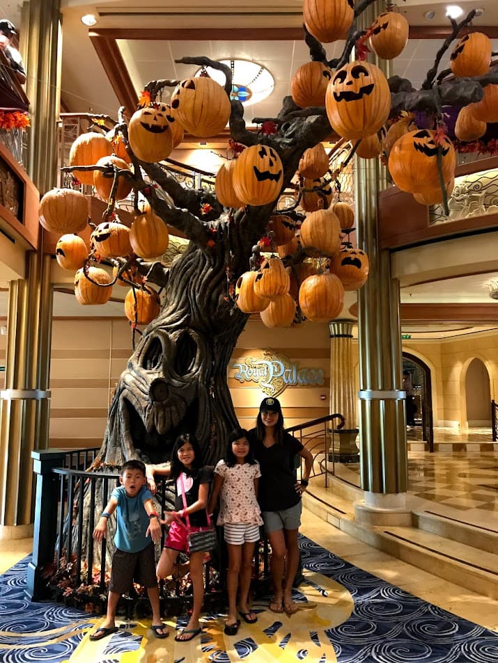 Advisor with three kids in front of a tree with hanging carved pumpkins.