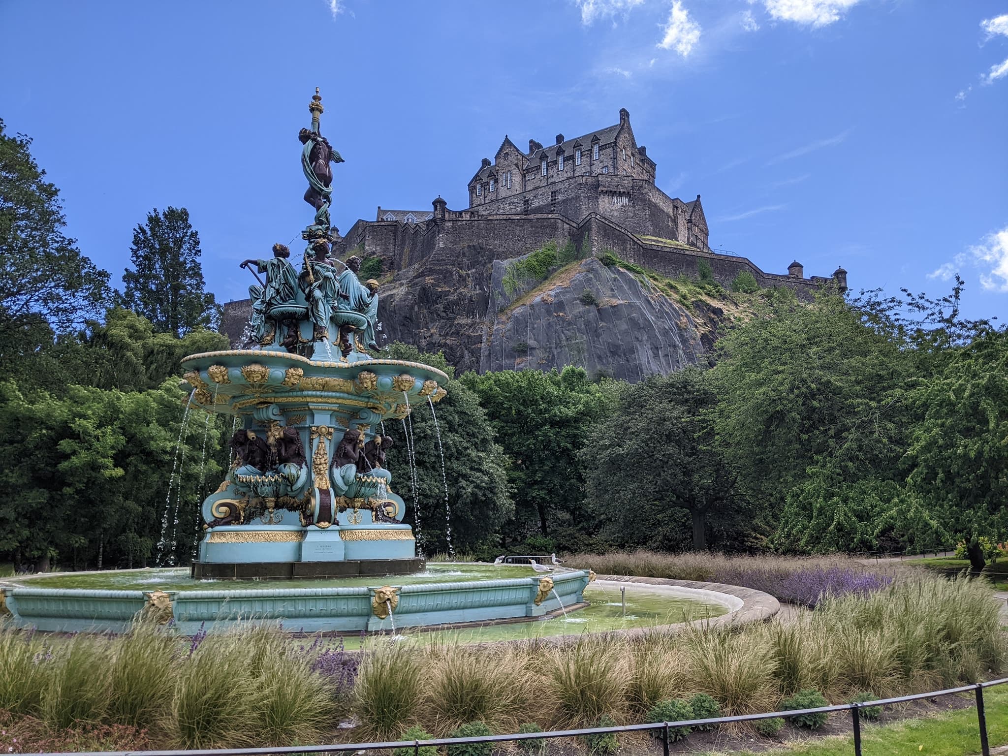 A beautiful fountain and house on top of hill.