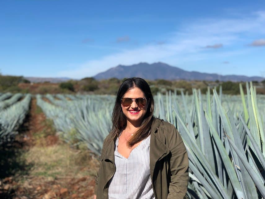 Picture of Mariela standing in front of aloe pants with a mountain in the background