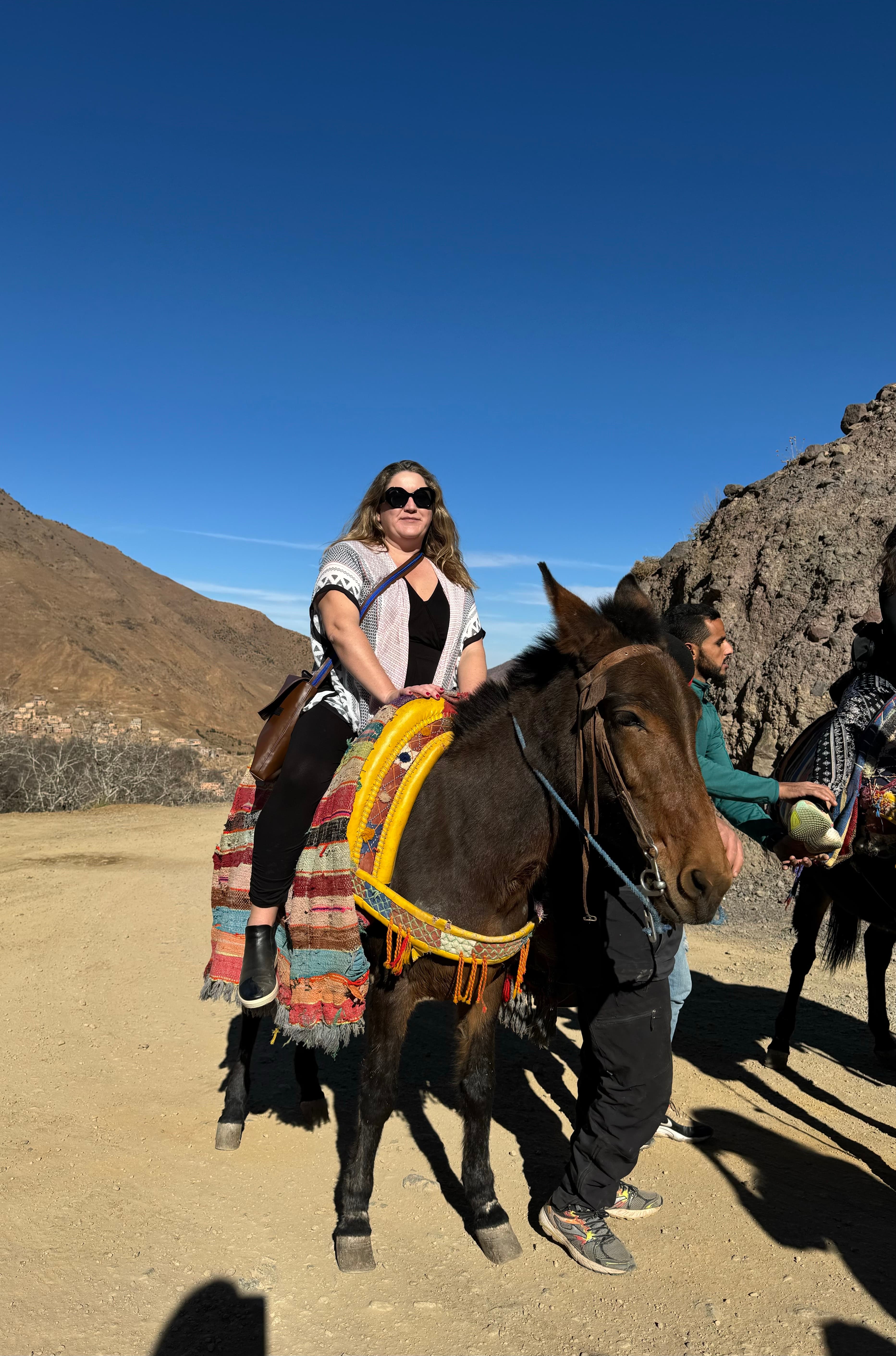 Karyn in a horse ready to go on a ride in a western setting.
