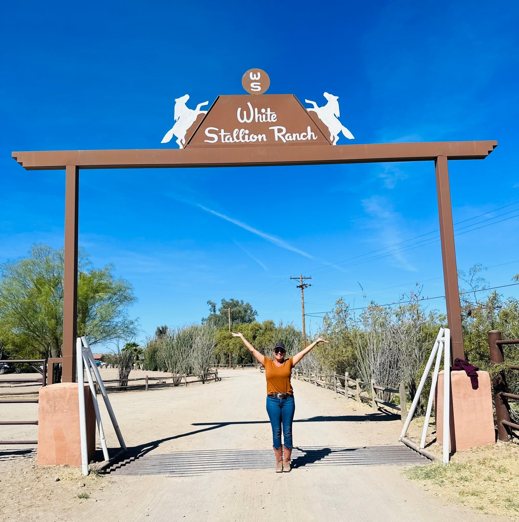 travel advisor Joanna Alejandro stands under wooden gate on a dirt road