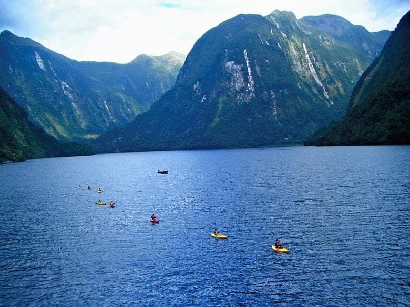 A lake with kayakers surrounded by mountains