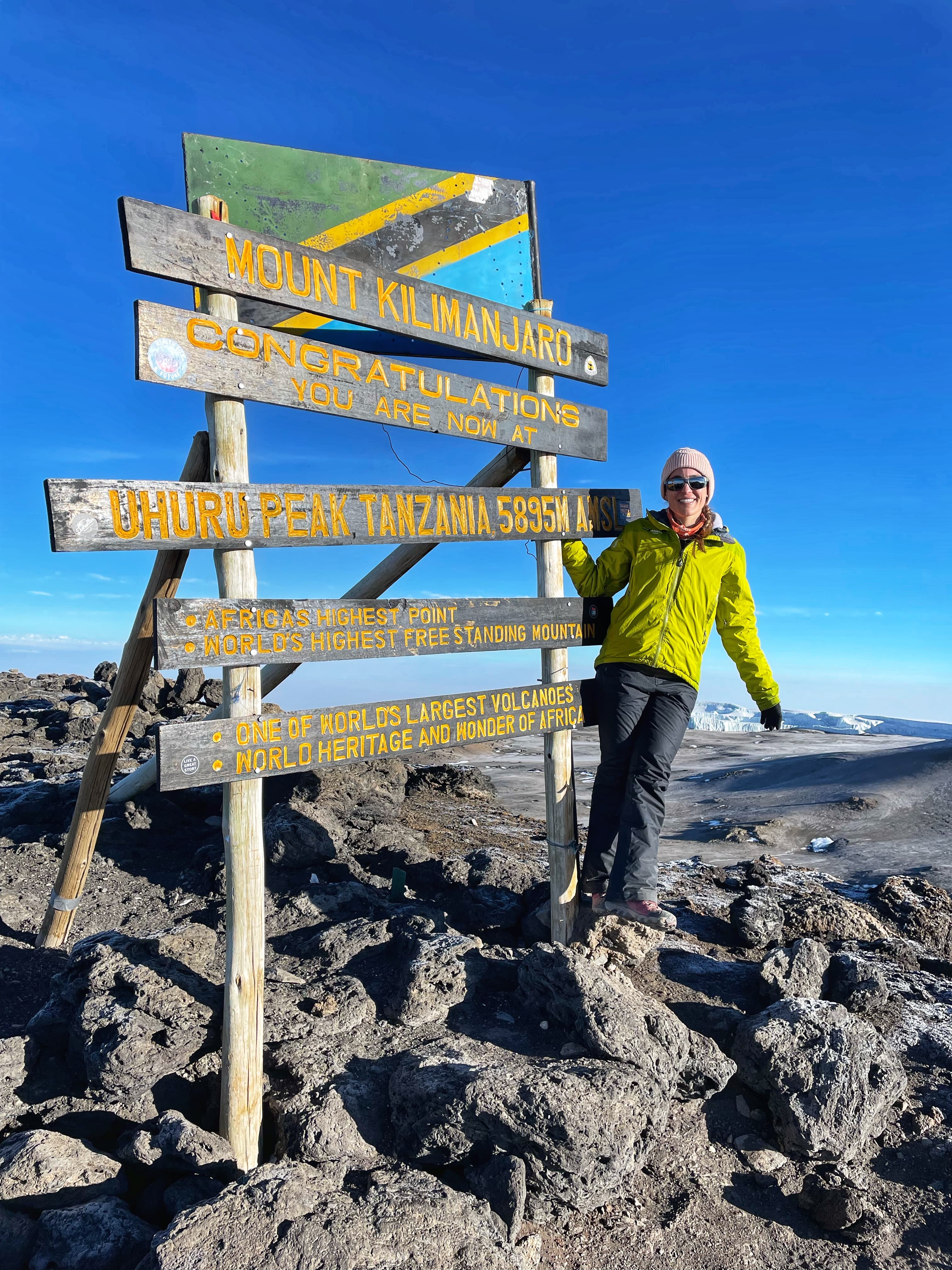 Picture of Amanda at Mount Kilimanjaro posing in front of a sign wearing a green top