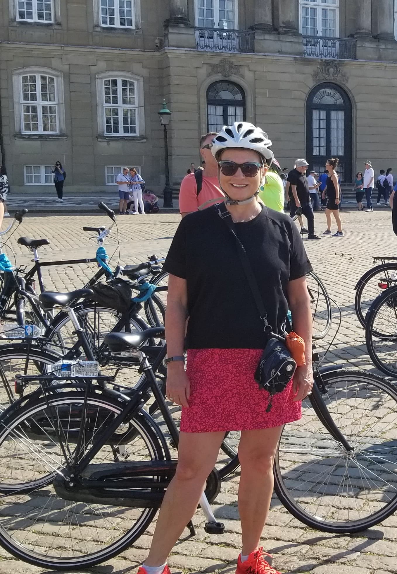 travel advisor Ann Pappas wears a bike helmet in a plaza next to many parked bicycles