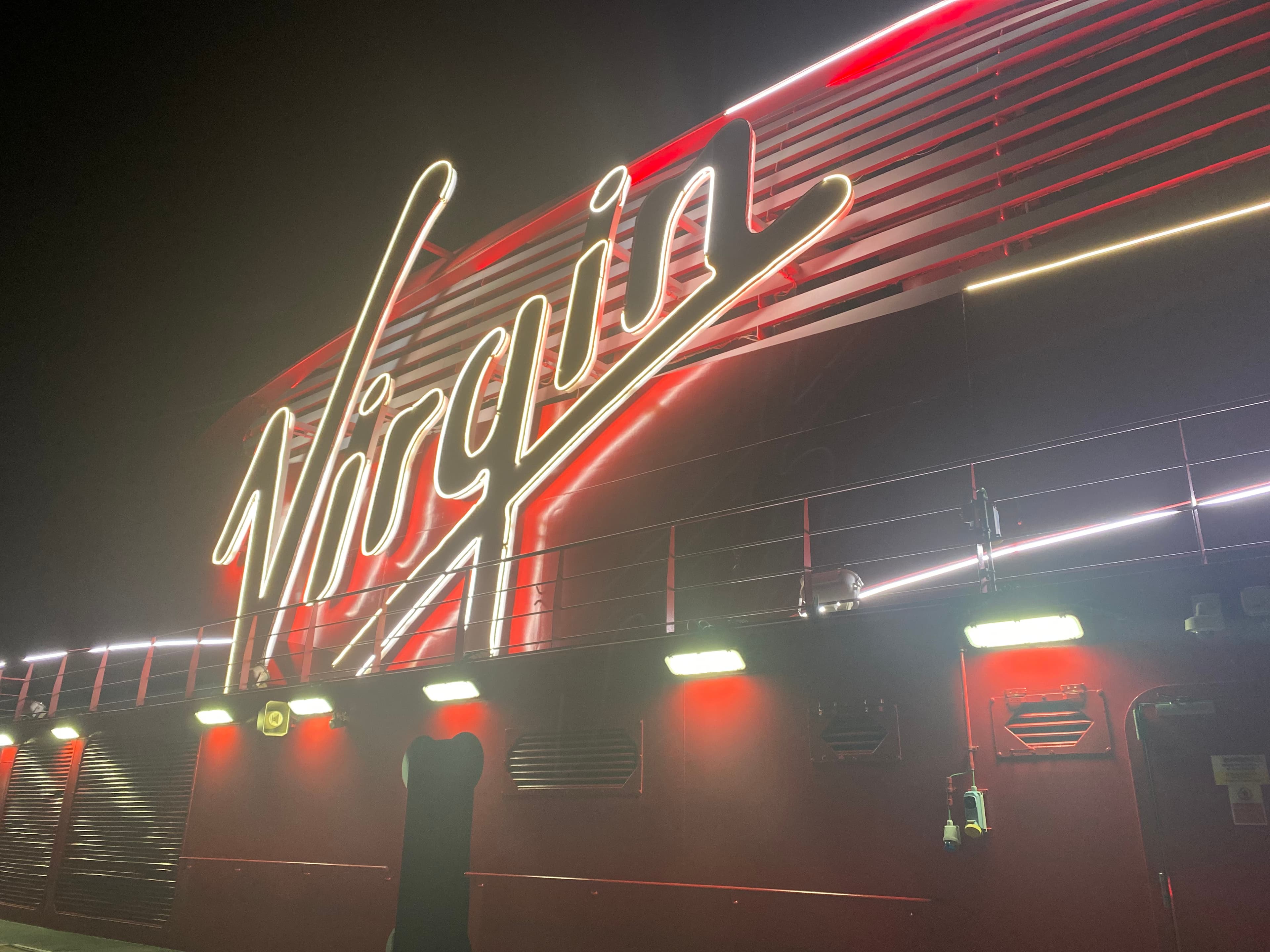 A photo of the Virgin Voyage sign lit up at night