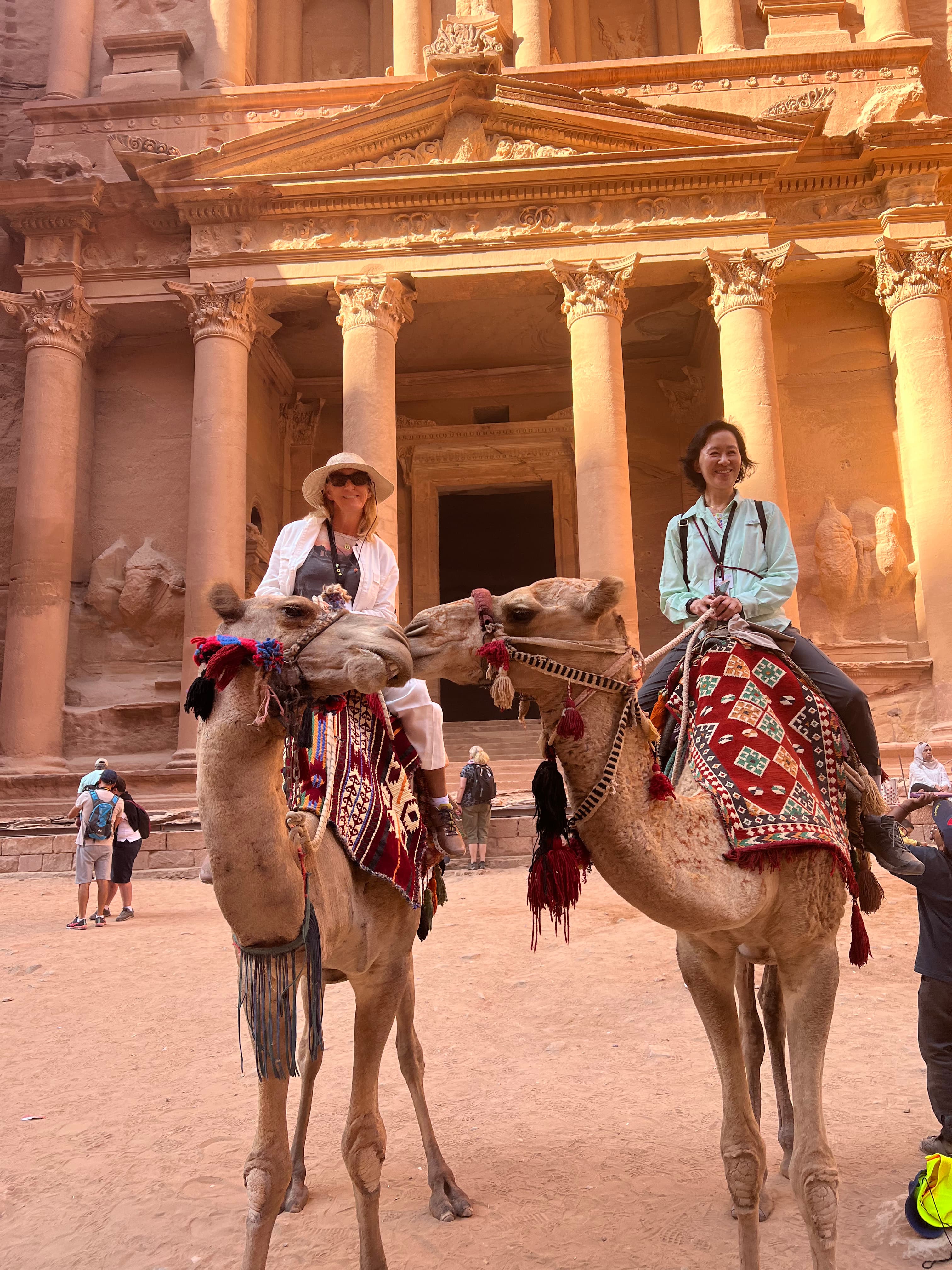 Susanne and a friend sitting on a camel in front of an ancient temple