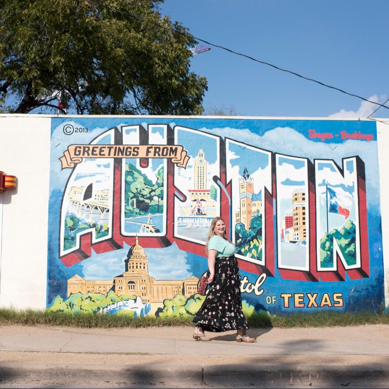 Advisor posing in front of a painted wall with Austin written on it.