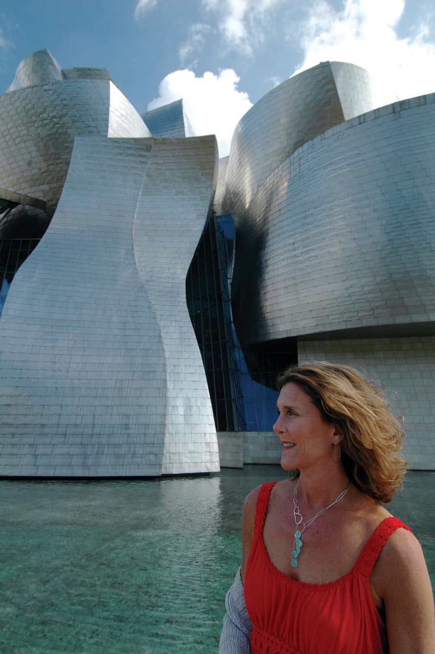 Melanie in a red dress with huge concrete architecture in background
