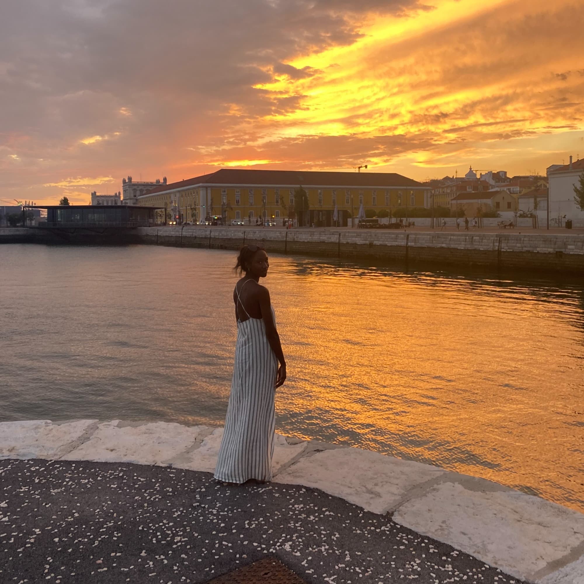Travel advisor in white dress standing by a water body.