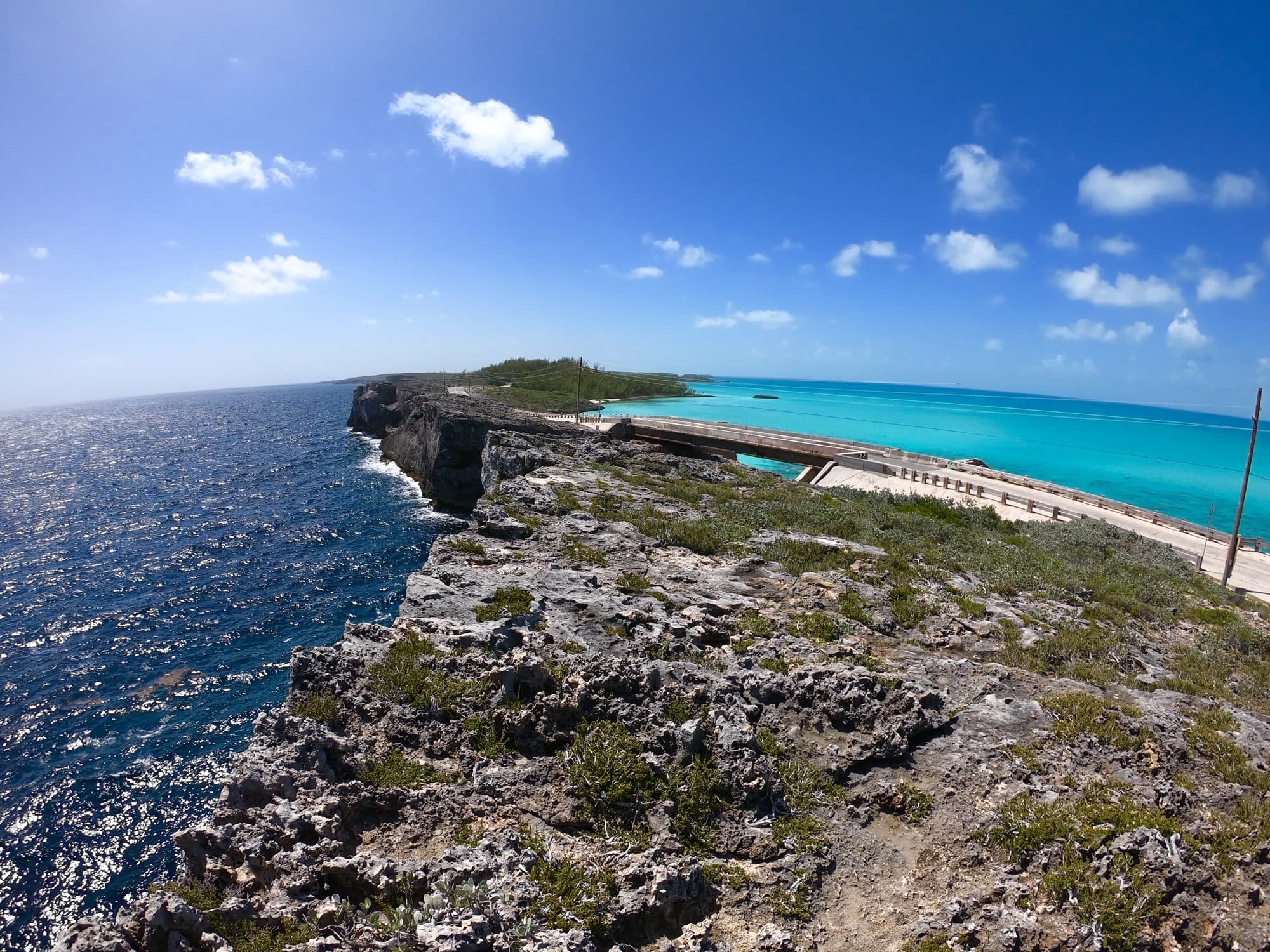 Picture of Glass Window Bridge surrounded by two different bodies of water against the blue sky and clouds