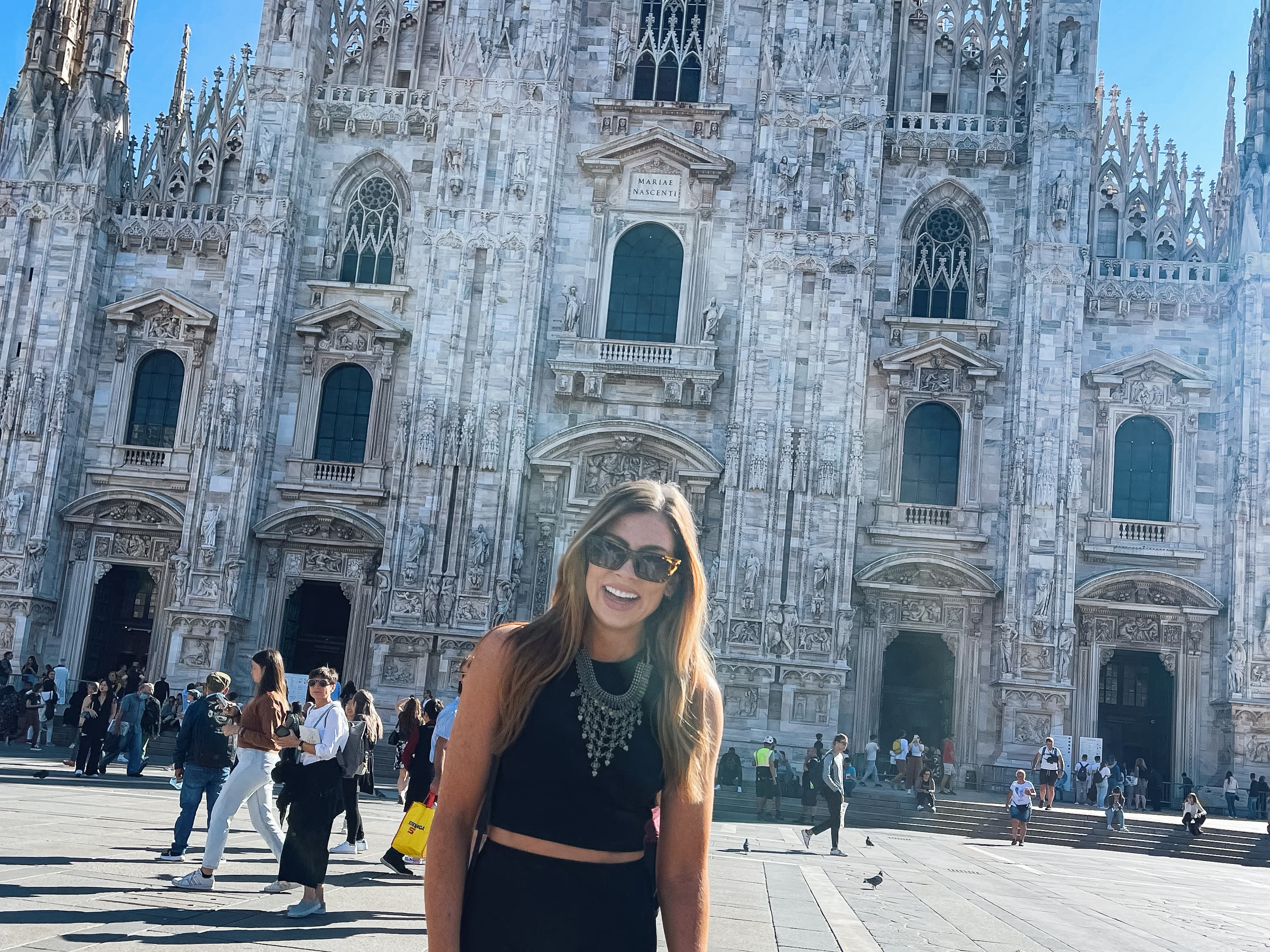 Visiting Duomo di Milano with people in the background walking on a sunny day
