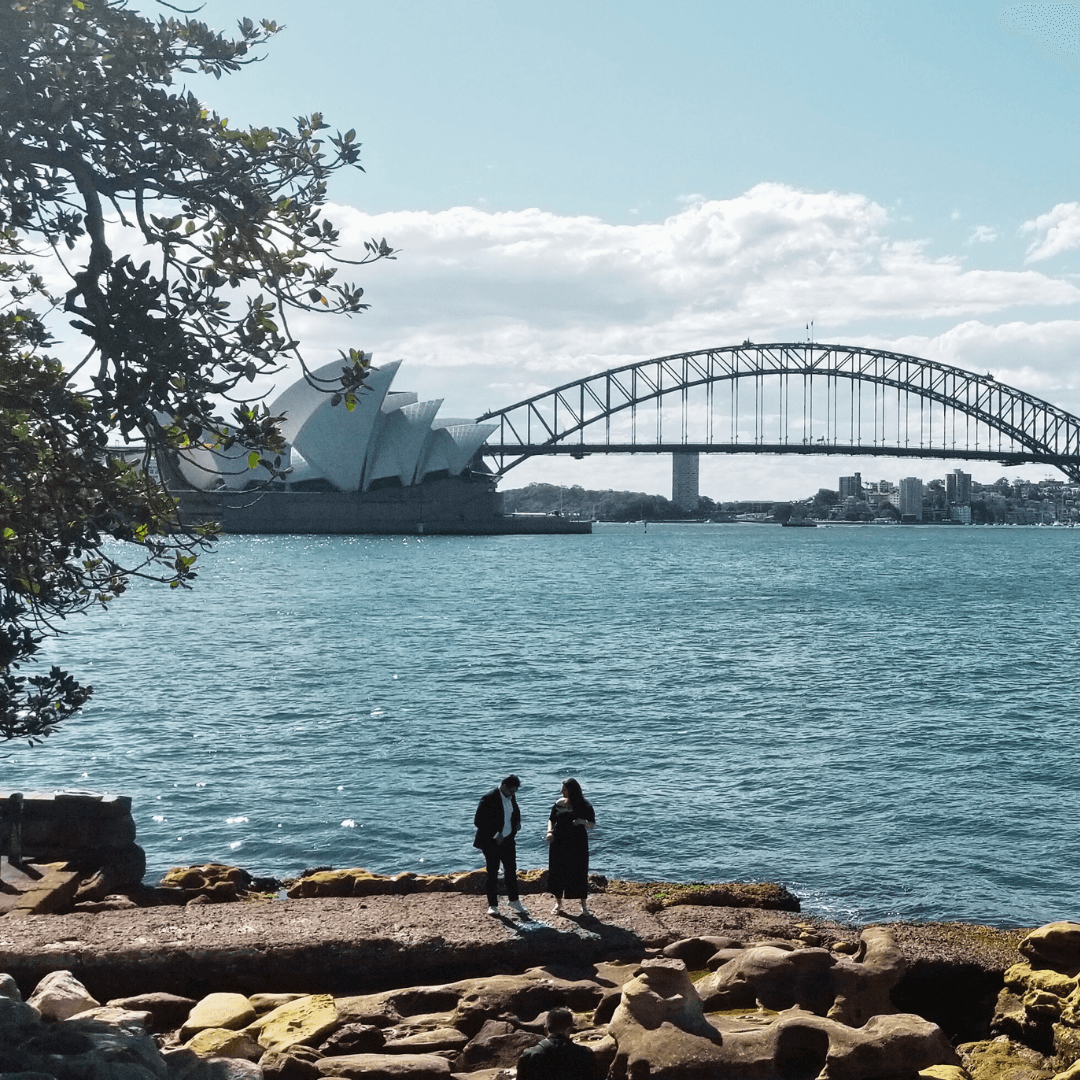 iconic bridge over water and two people standing on a rocky shore