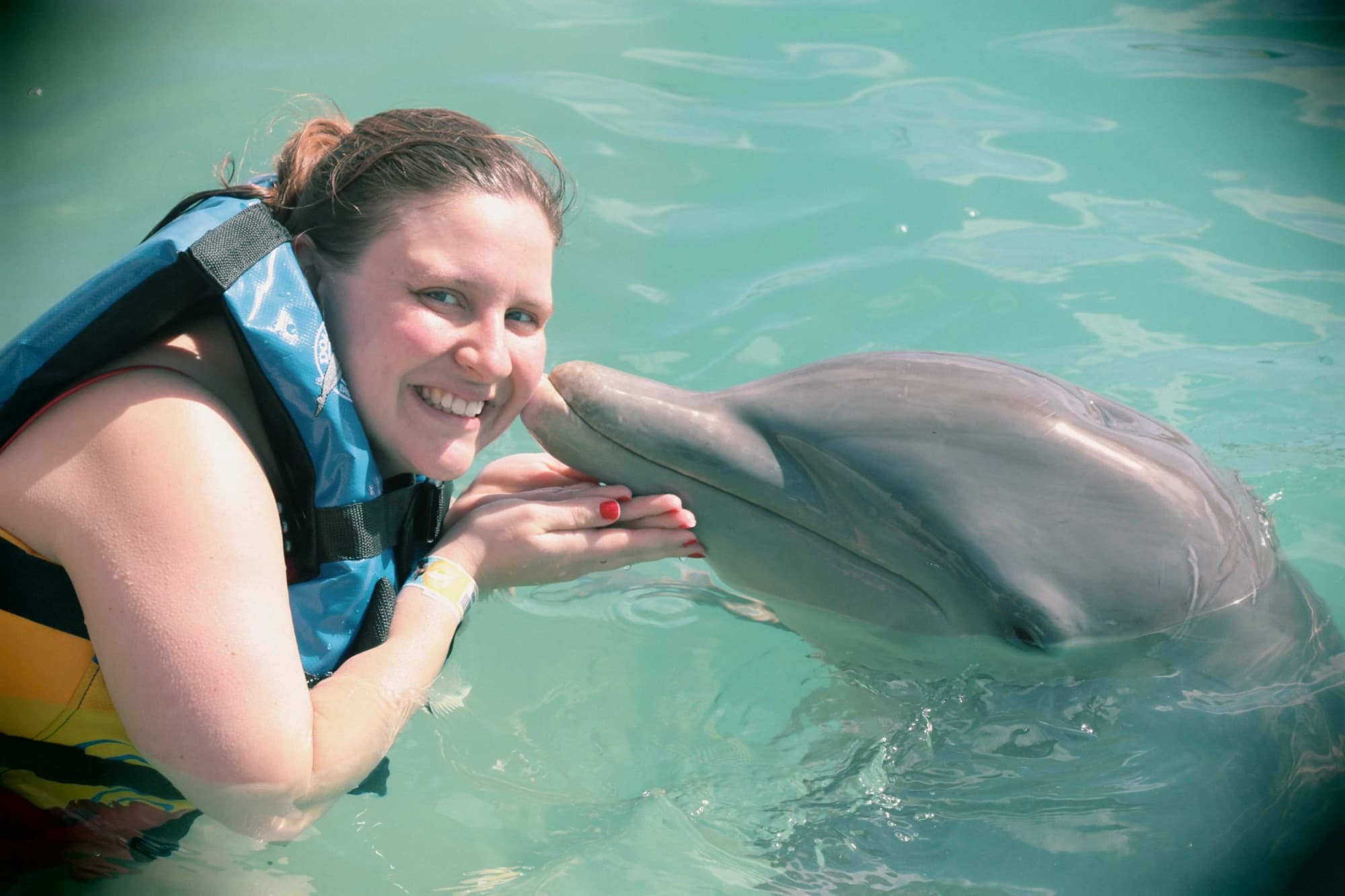A woman with dolphin in water body.