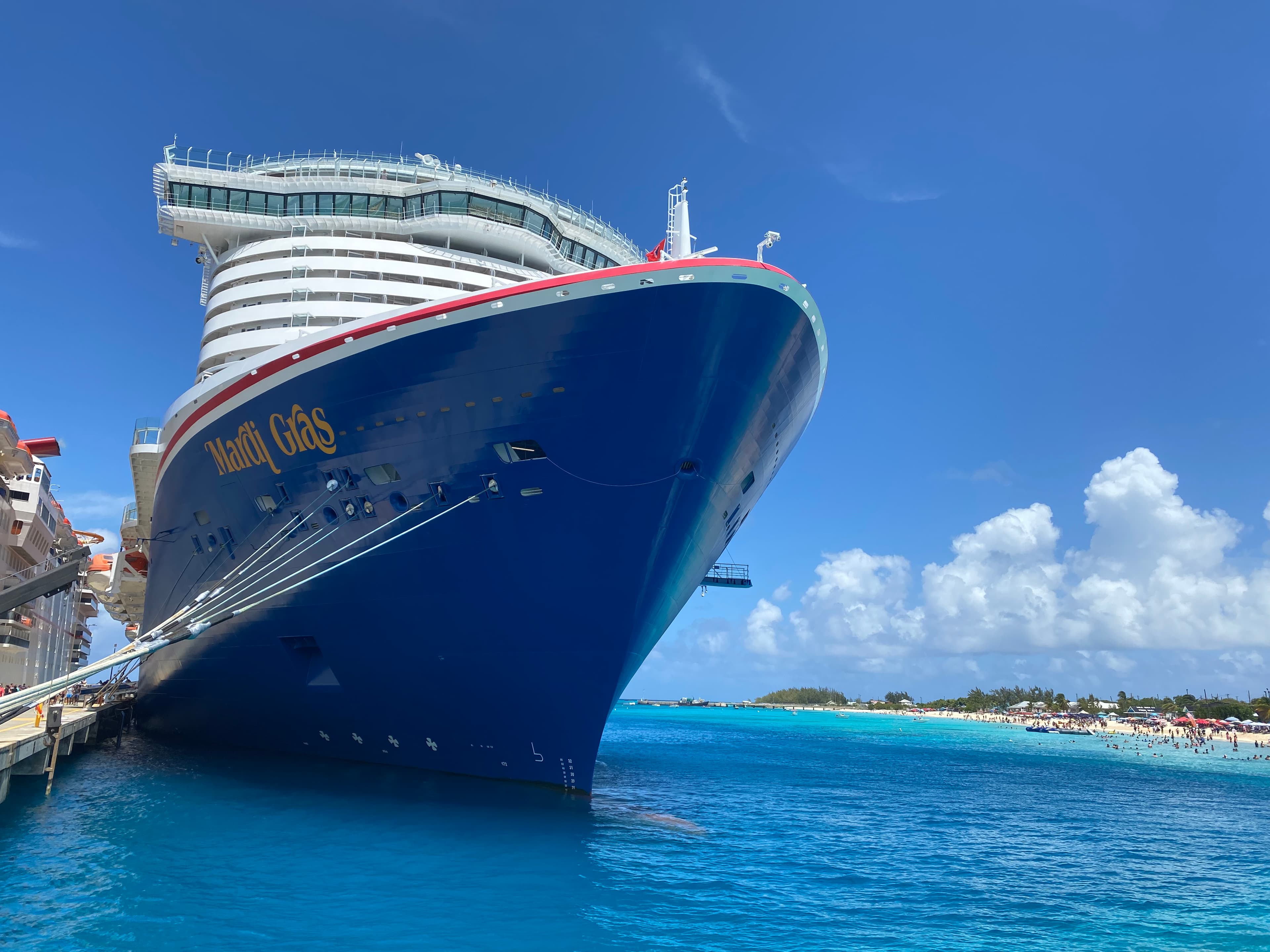 A blue cruise ship docked over bright blue water
