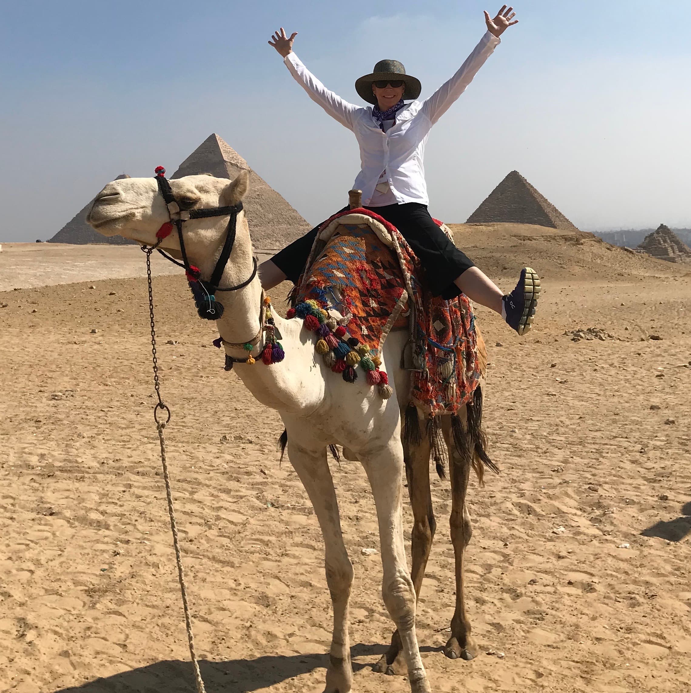 Travel advisor riding on a camel in front of the pyramids
