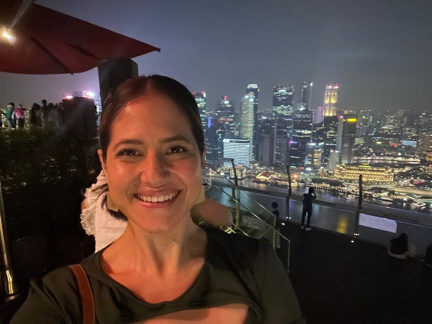 Mariela posing for a selfie in front of the Singapore skyline at nighttime