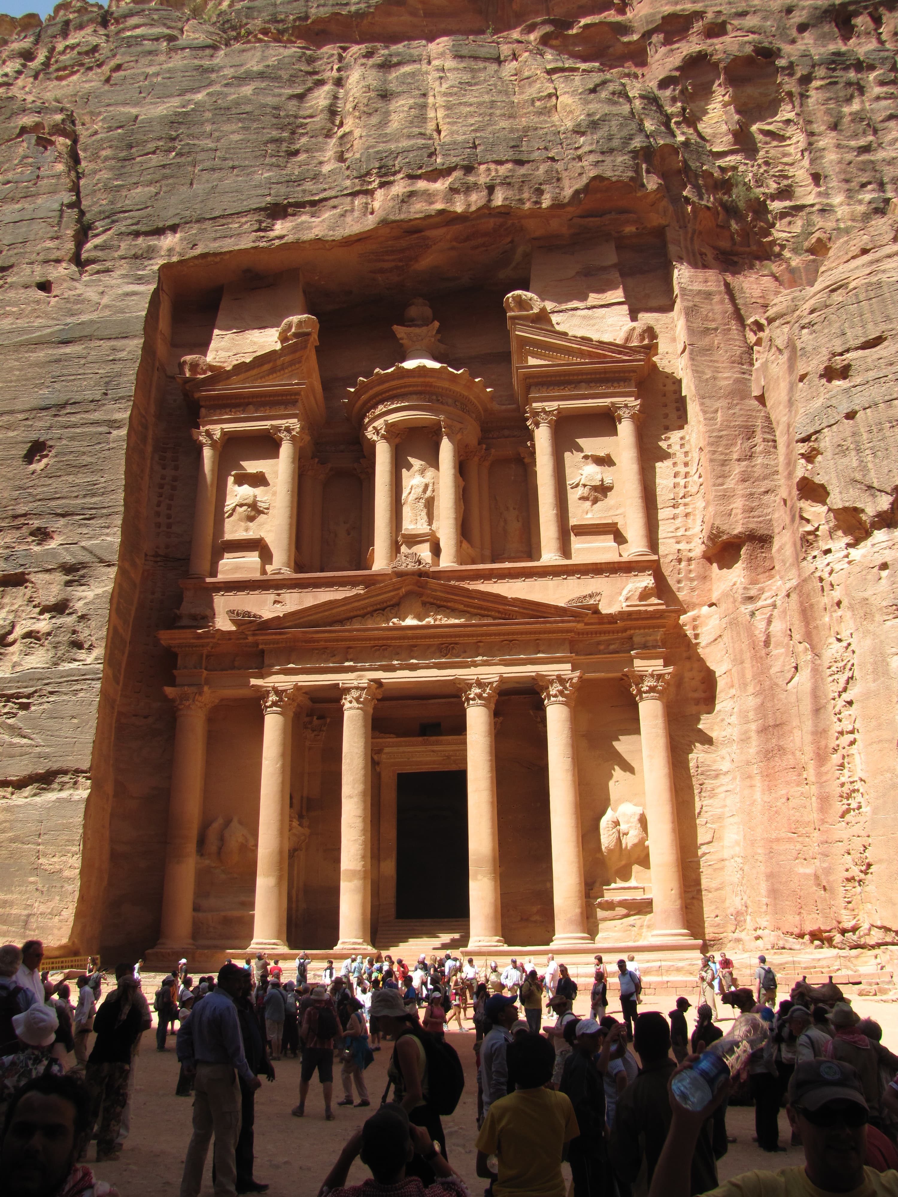 A picture of a red building in Jordan with a crowd.