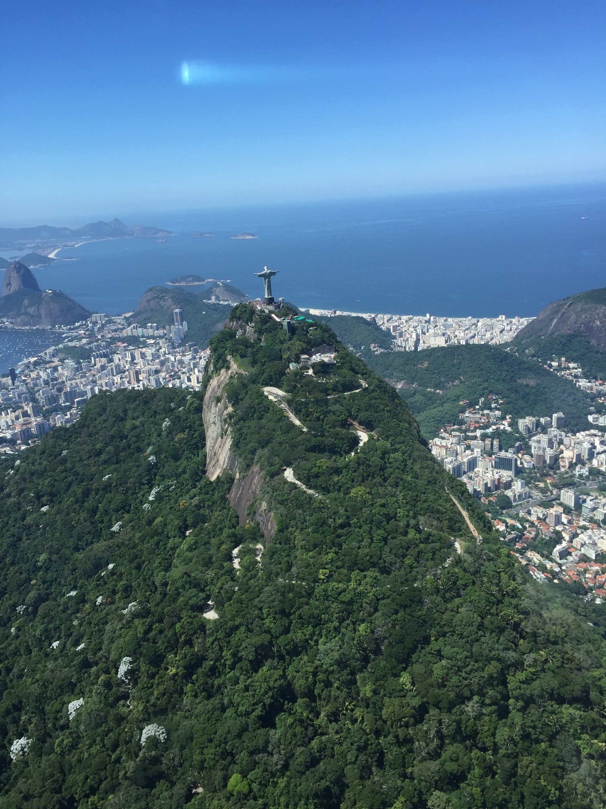 statue atop a cliff over a coastal city