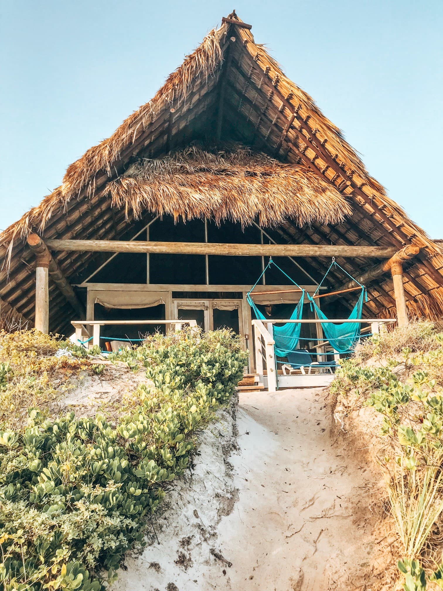 A dirt path leading to a straw hut with blue swings