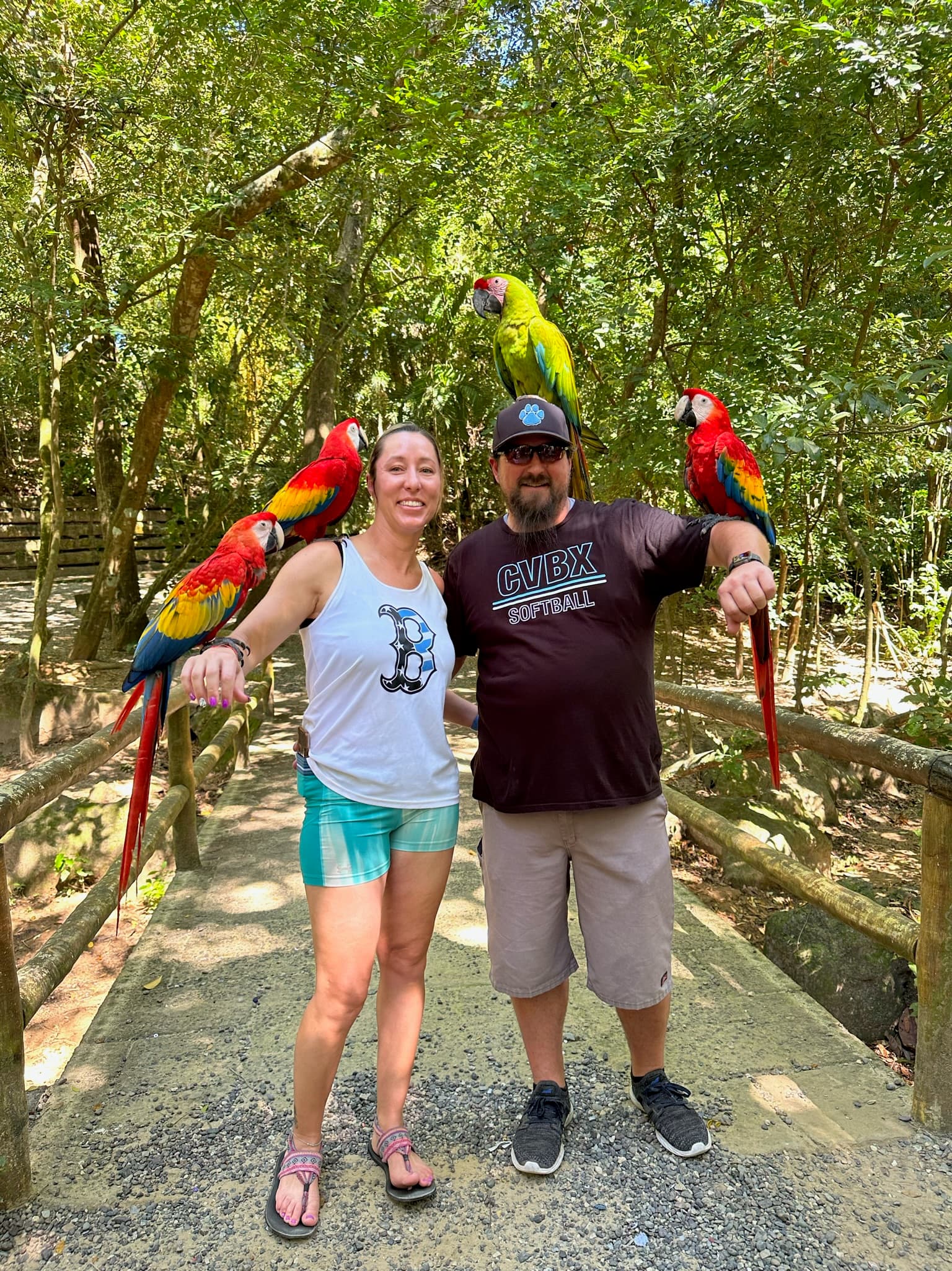 Picture of Amanda and partner holding parrots in front of trees