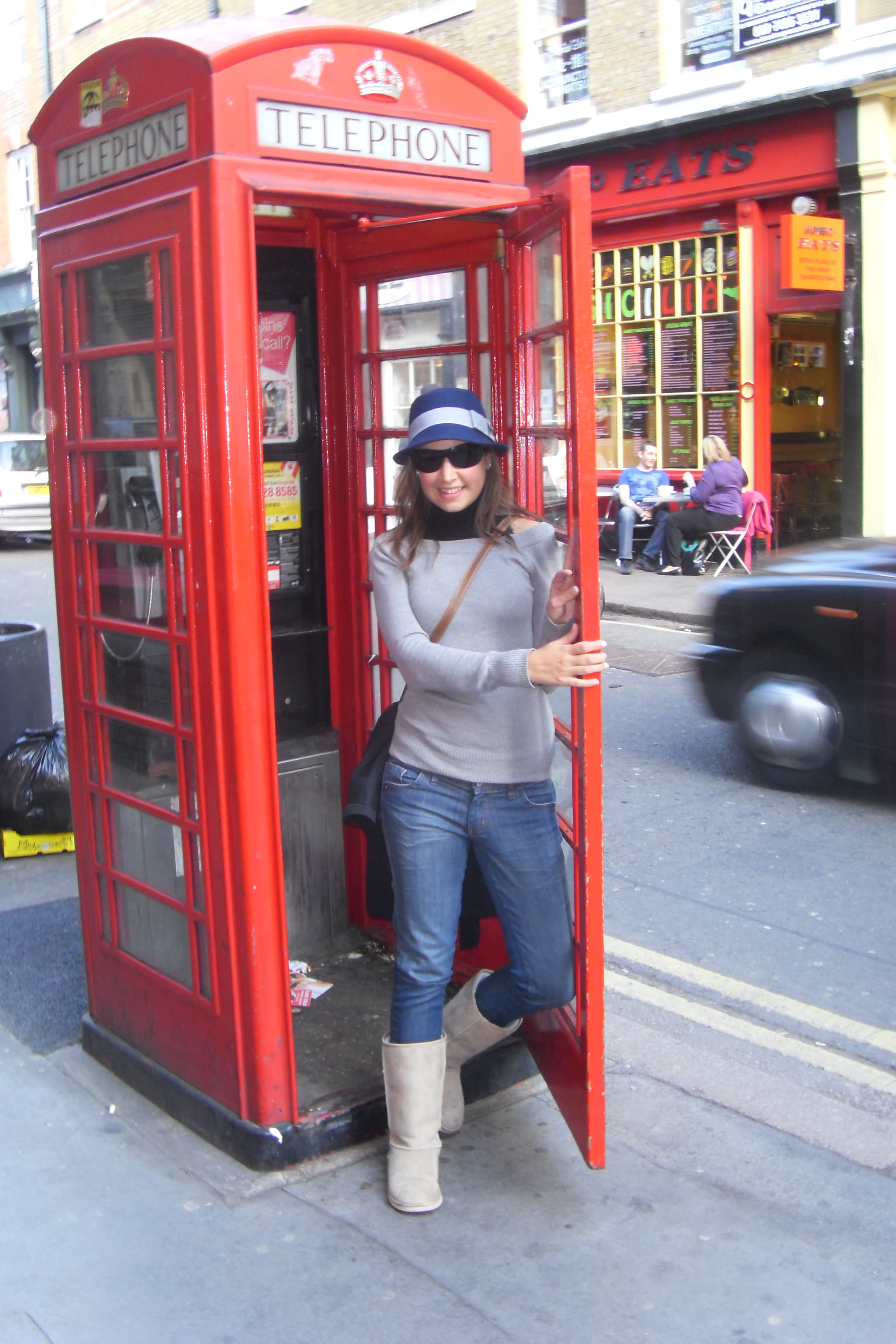 Maggie in a grey shirt in a red phonebooth.