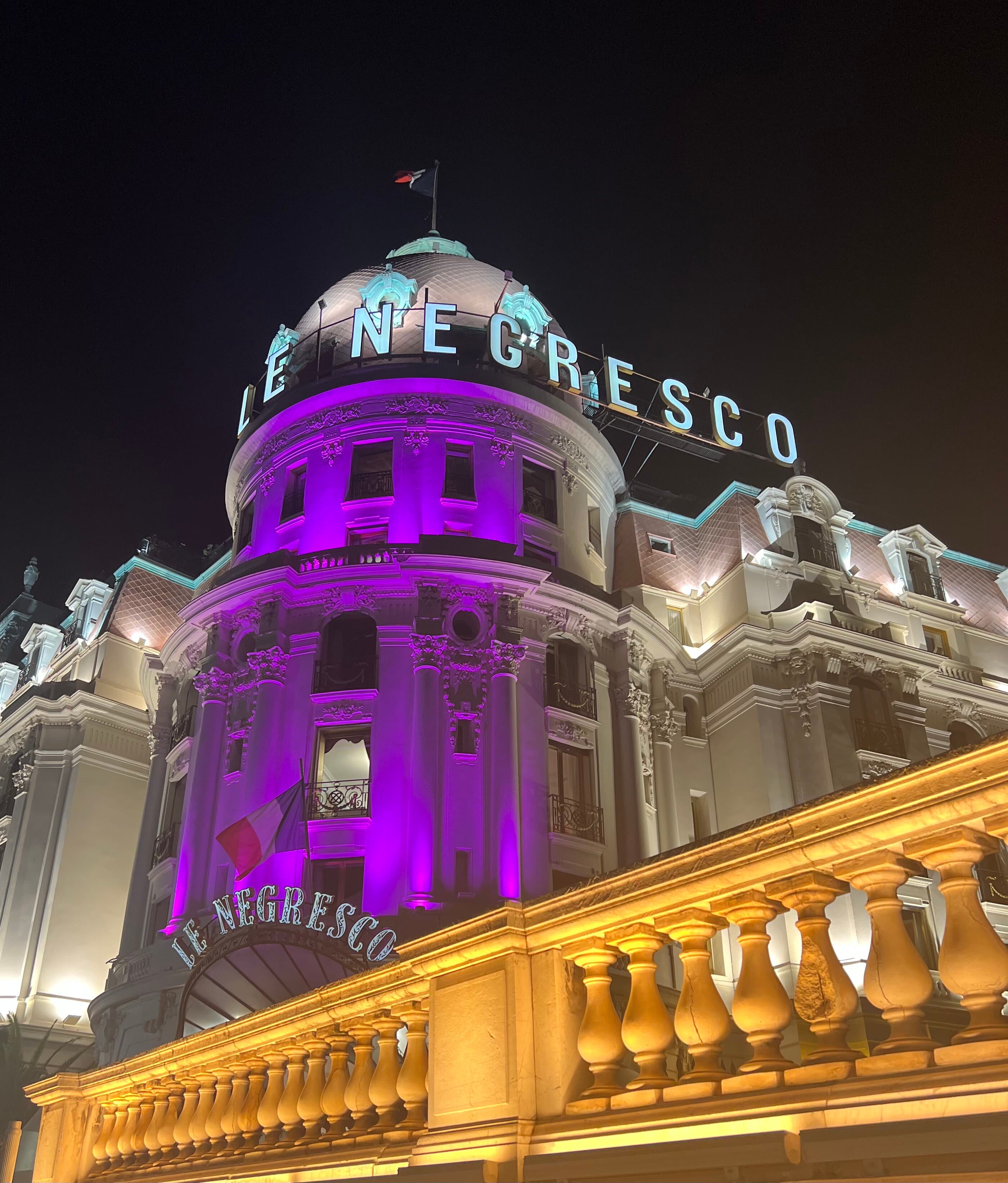 A picture of Le Negresco hotel lit up with a purple light at nighttime