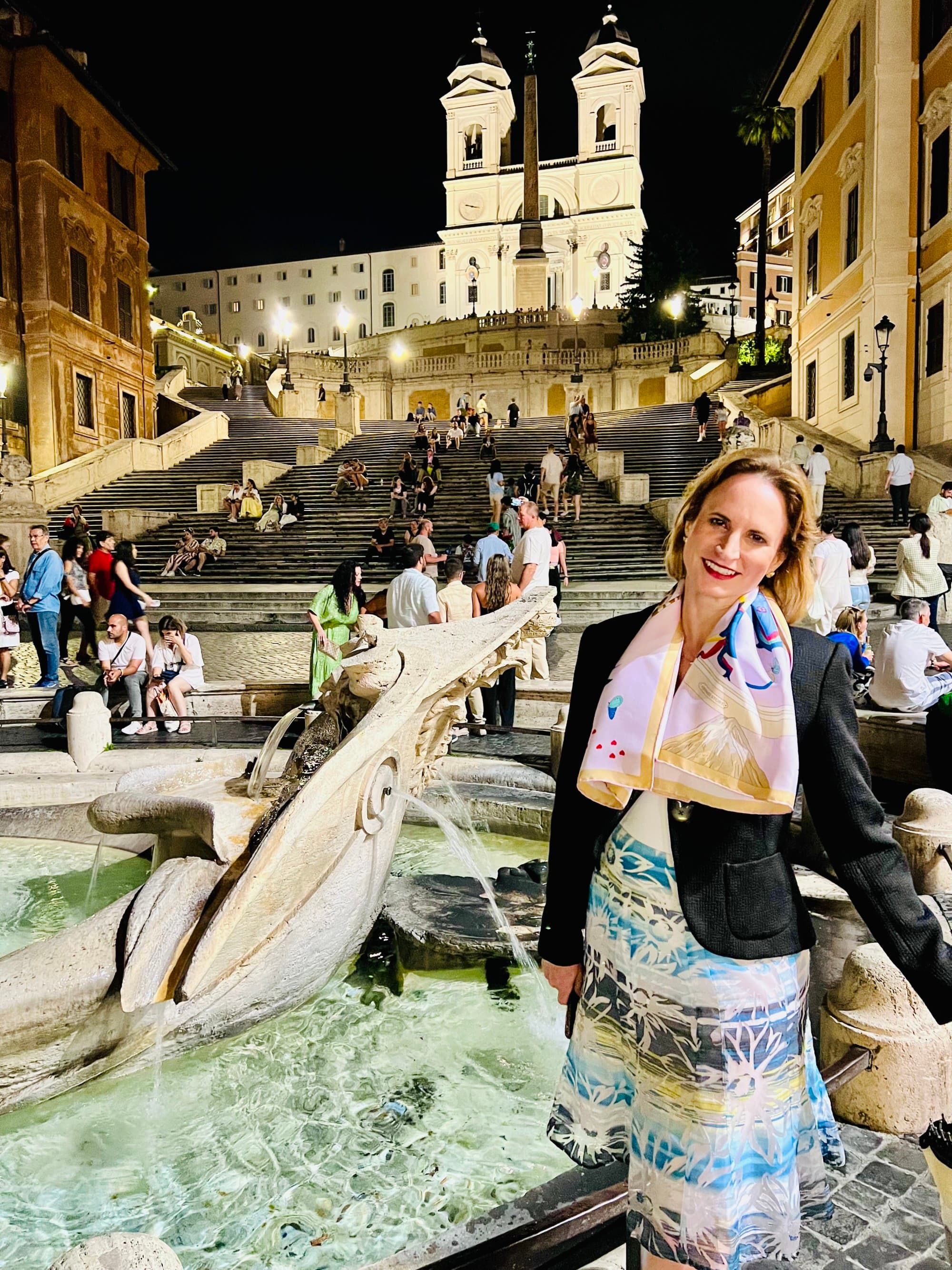 A woman in front of a fountain in city at night,