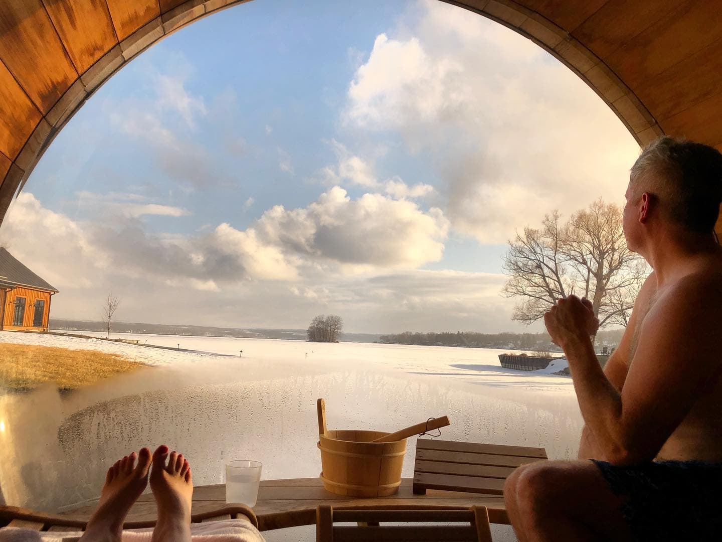 Travel advisor posing inside a sauna looking out of a window to a snowy field