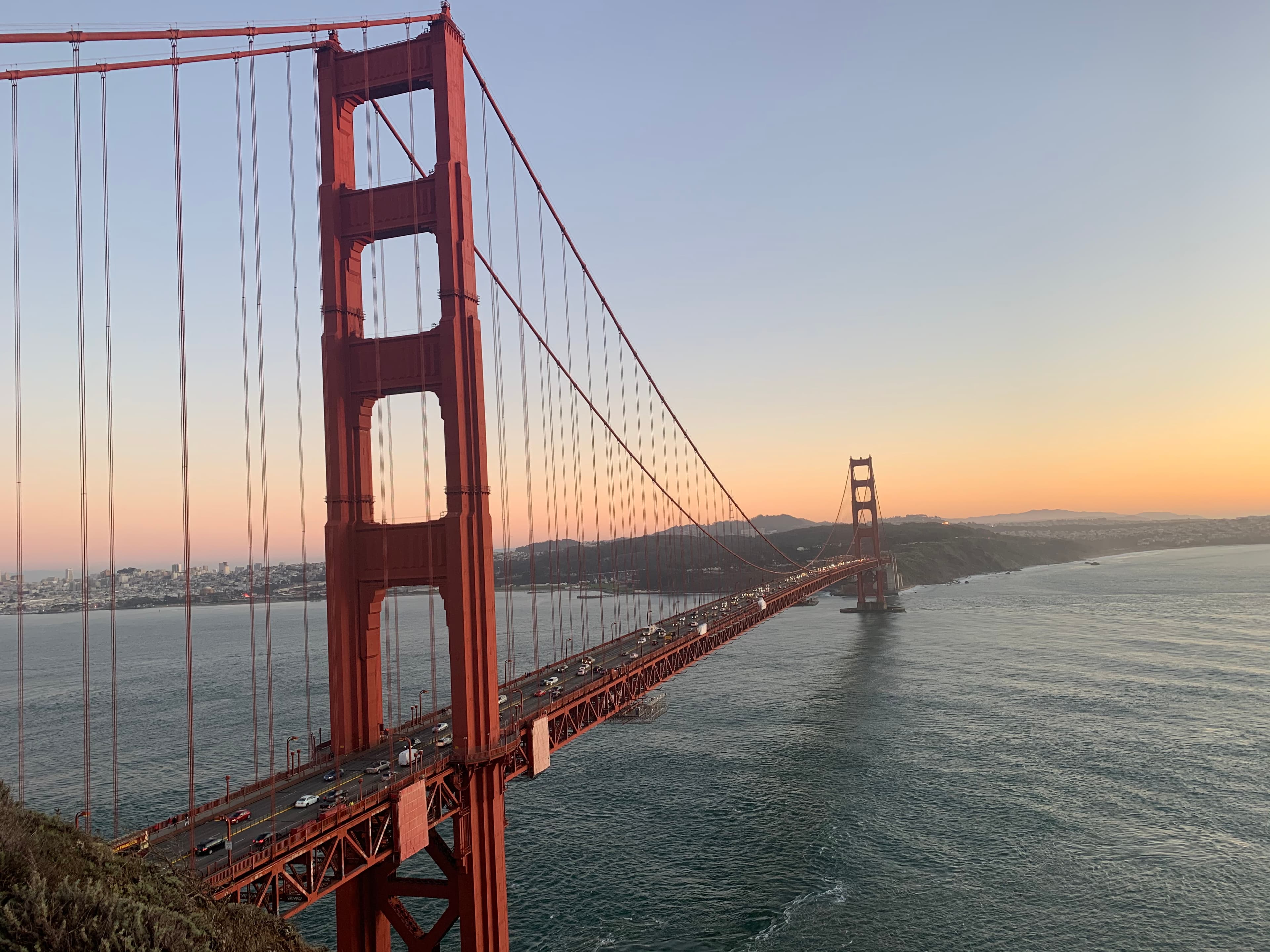 A view of the Golden Gate Bridge at sunset surrounded by water