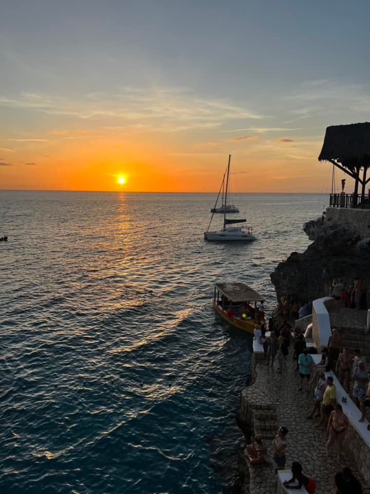 A sunset view over the water with boats and a coastline in the distance