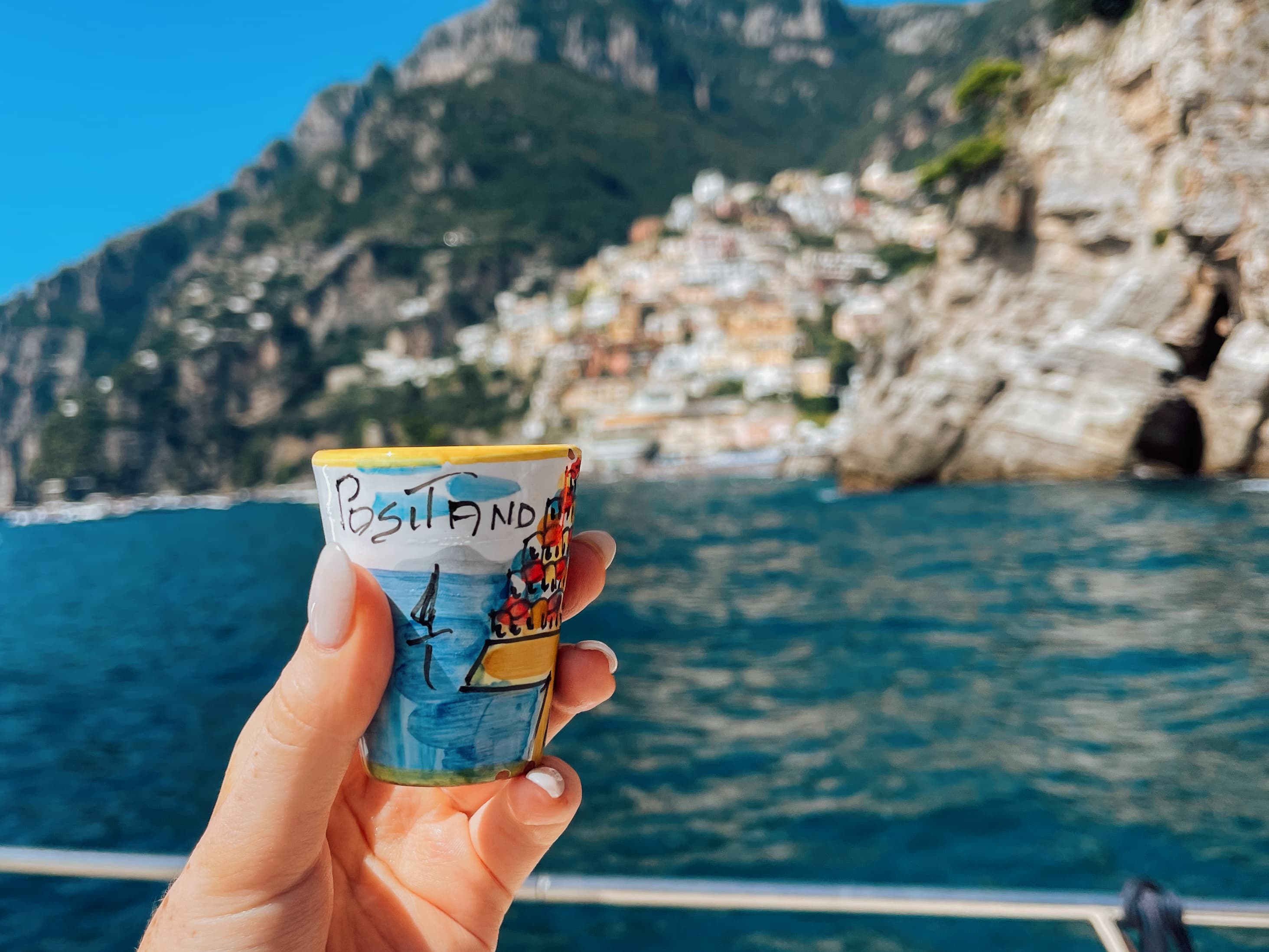 Holding a travel souvenir over the sea and Italian coast