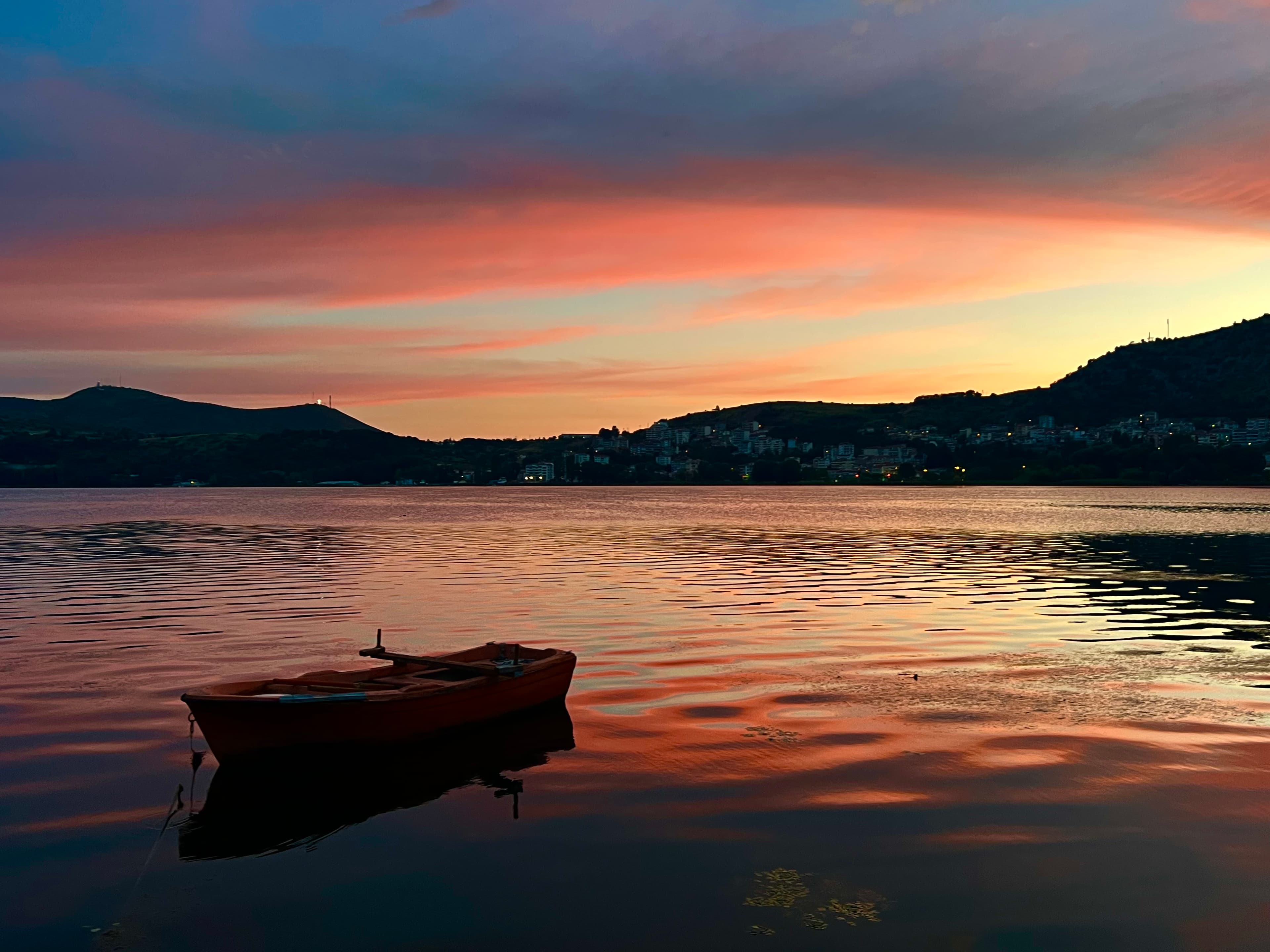 A boat on a lake at sunset with mountains in the background