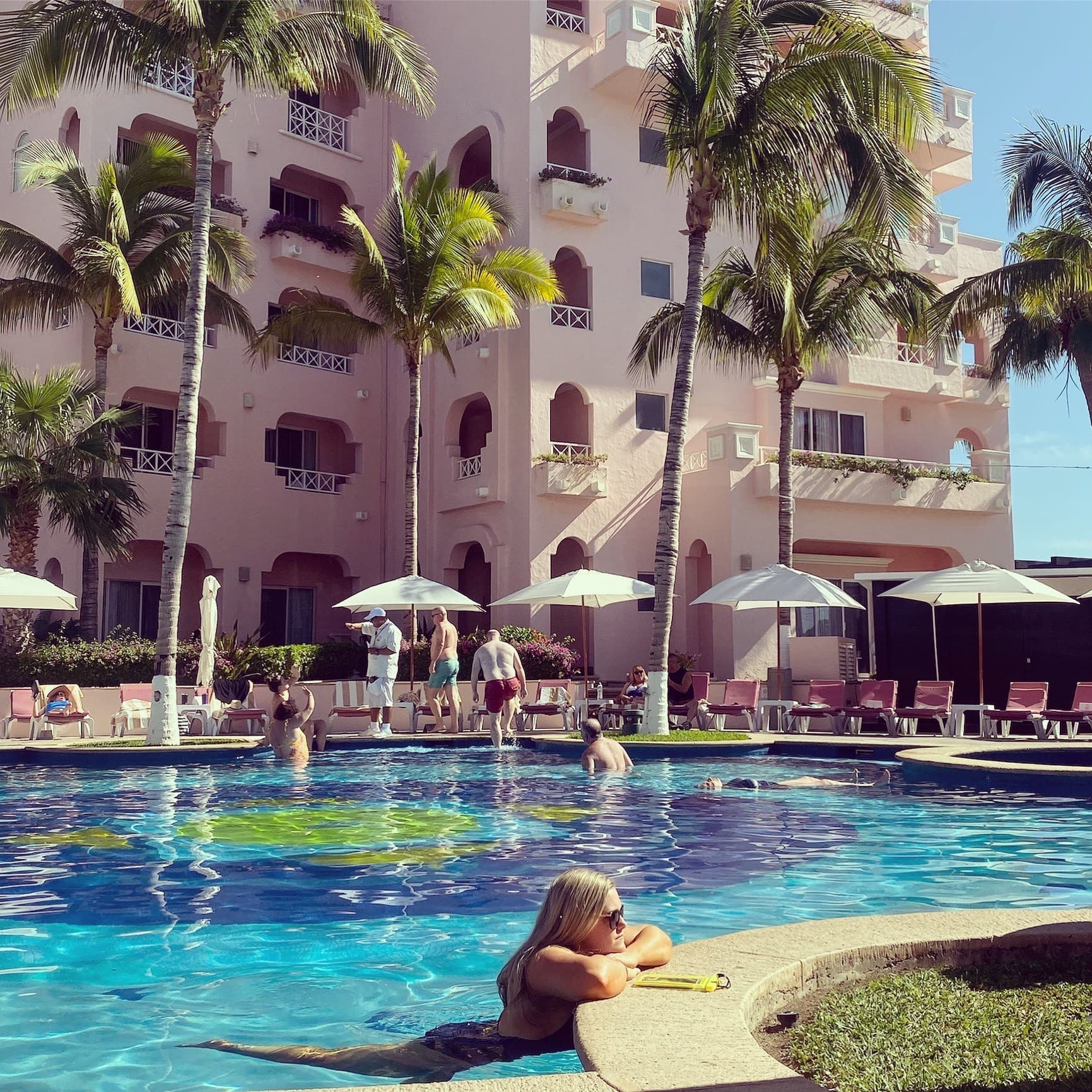 Picture of Nicole in pool at a resort with palm trees surrounding it.
