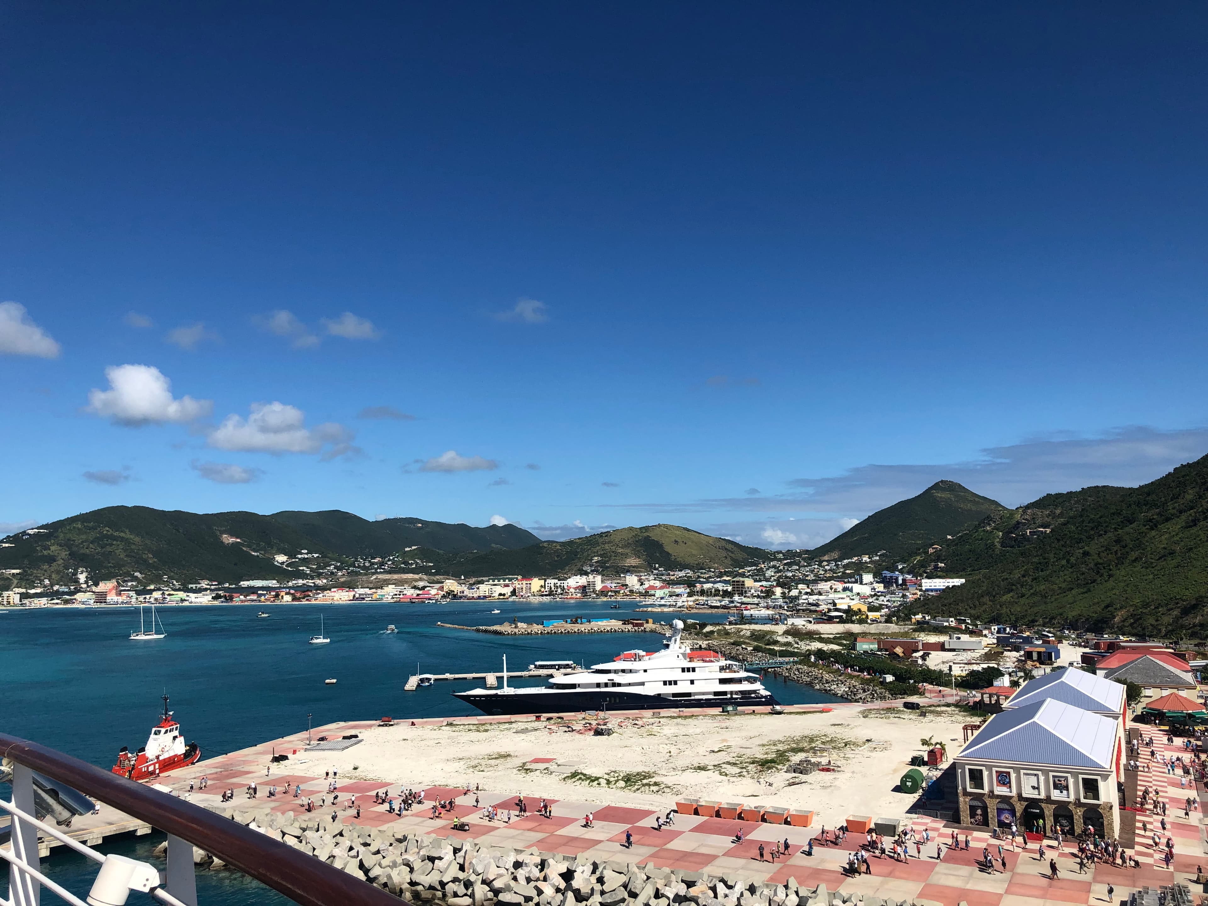 A picture of a cruise port with green mountains and blue water in the background