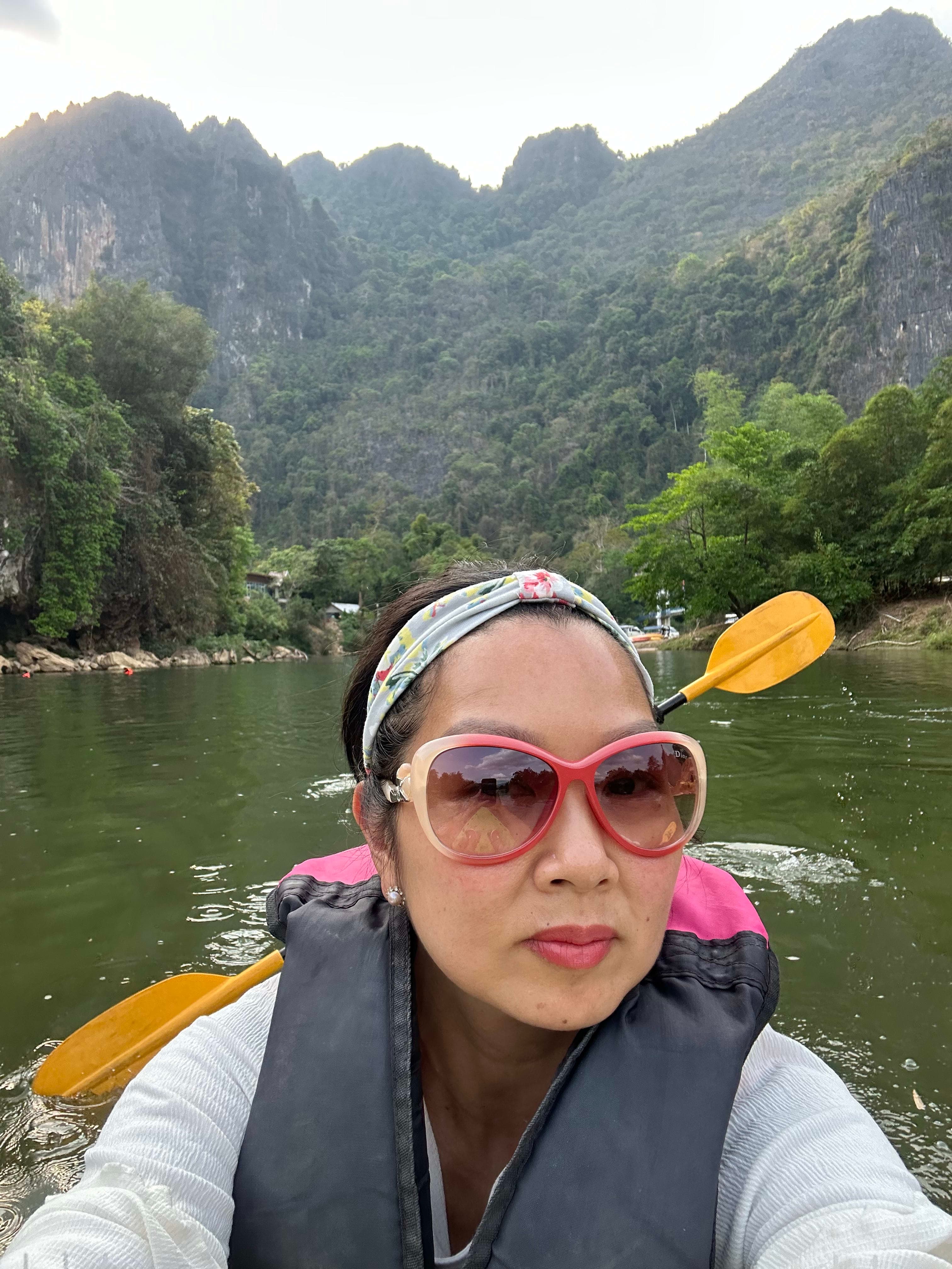 Picture of Anne in a kayak on a river surrounded by lush, green, mountains