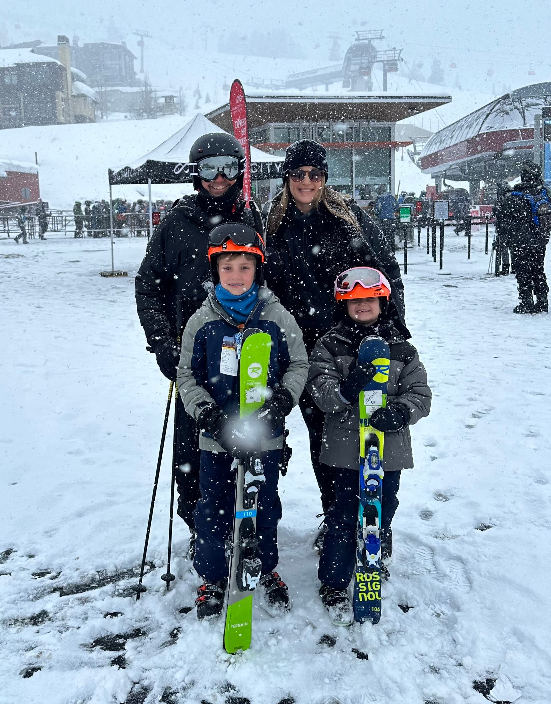 A picture of a man and a woman and two small children posing with their ski gear