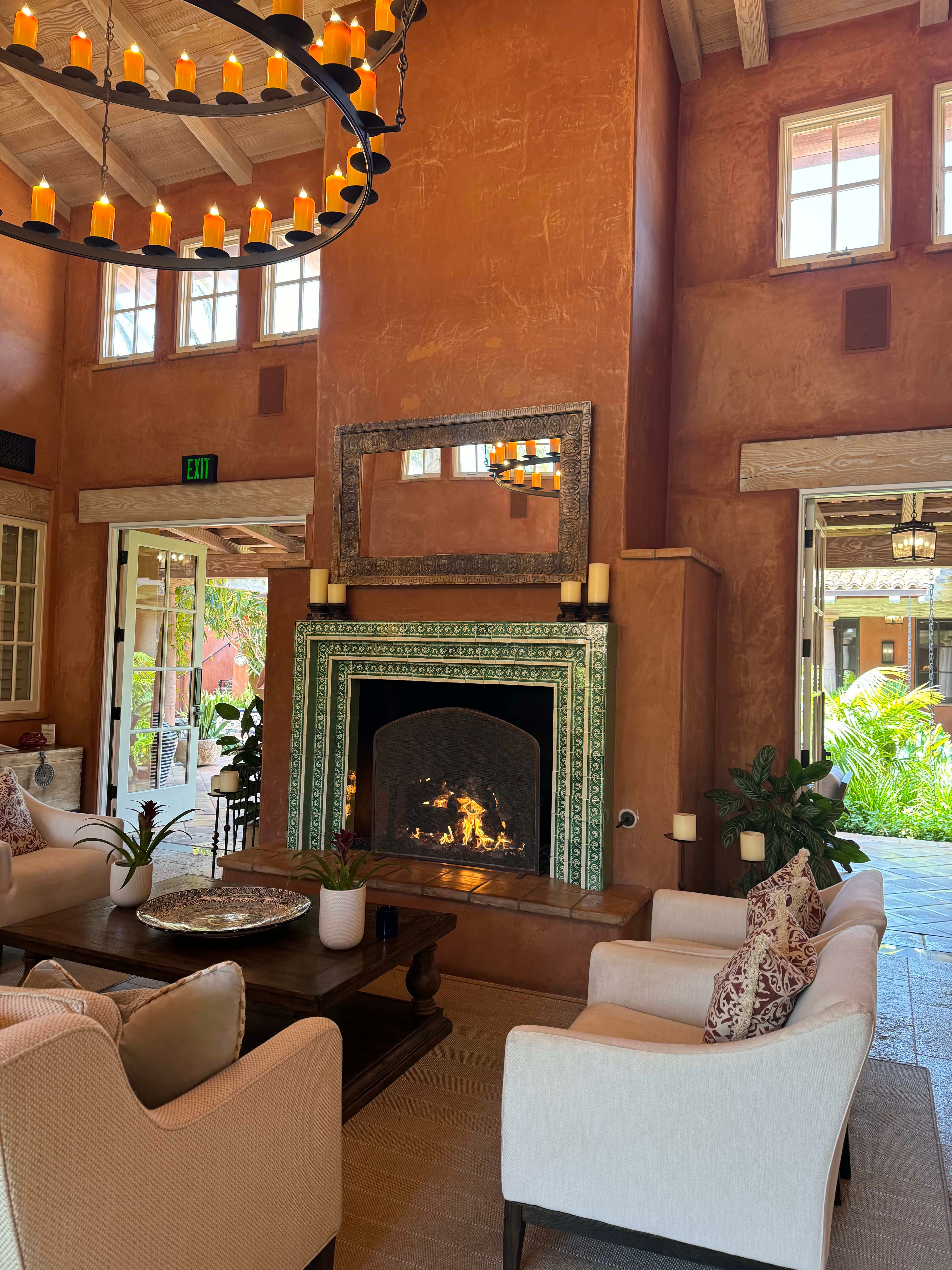 Hotel lobby with white couches, a fireplace and a round chandelier overhead.