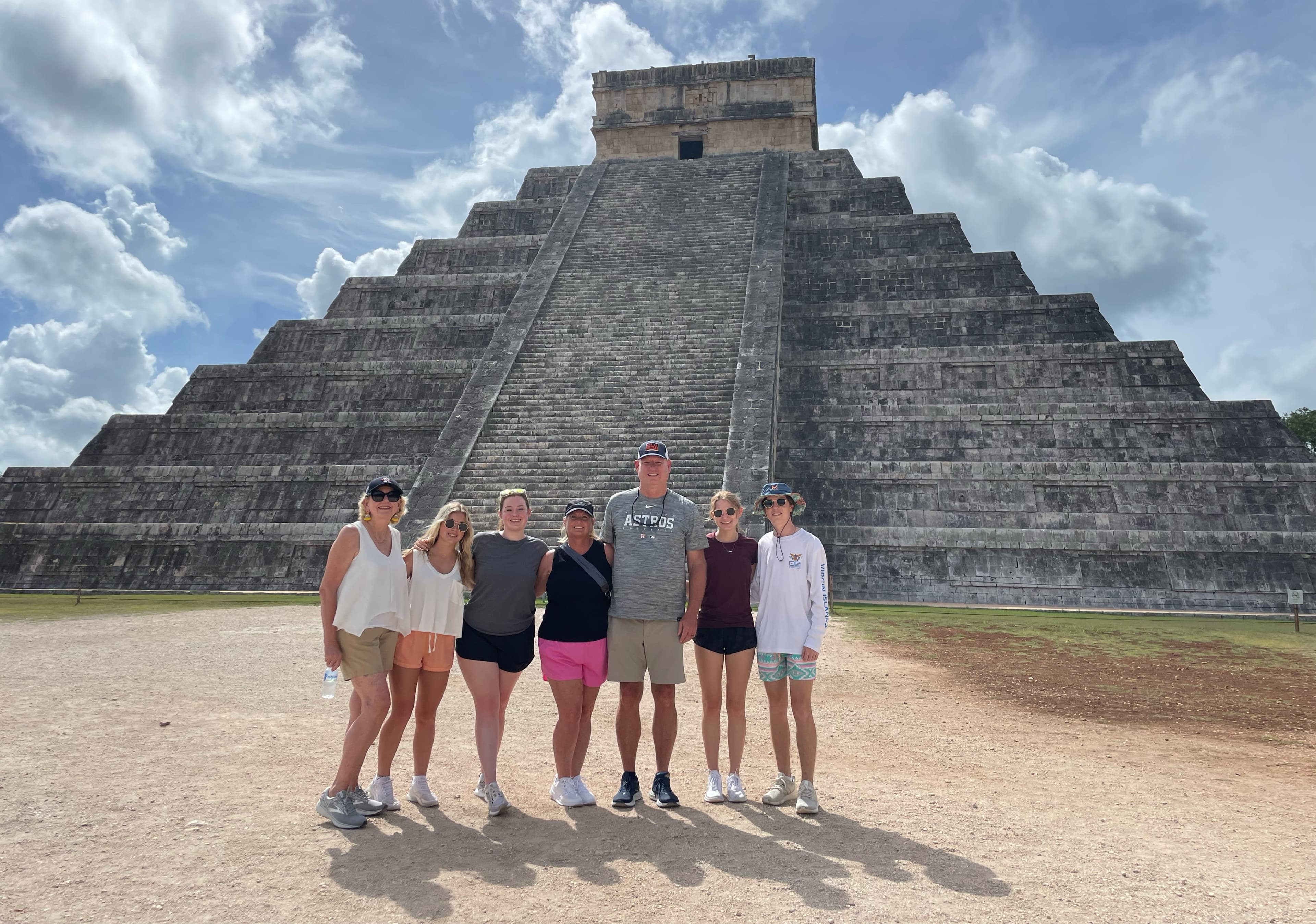 A family posing for a photo in front of a large stone pyramid in Mexico